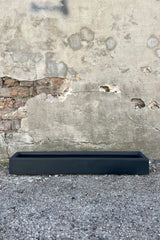 Photo of long narrow black Balcony Planter against a cement wall.