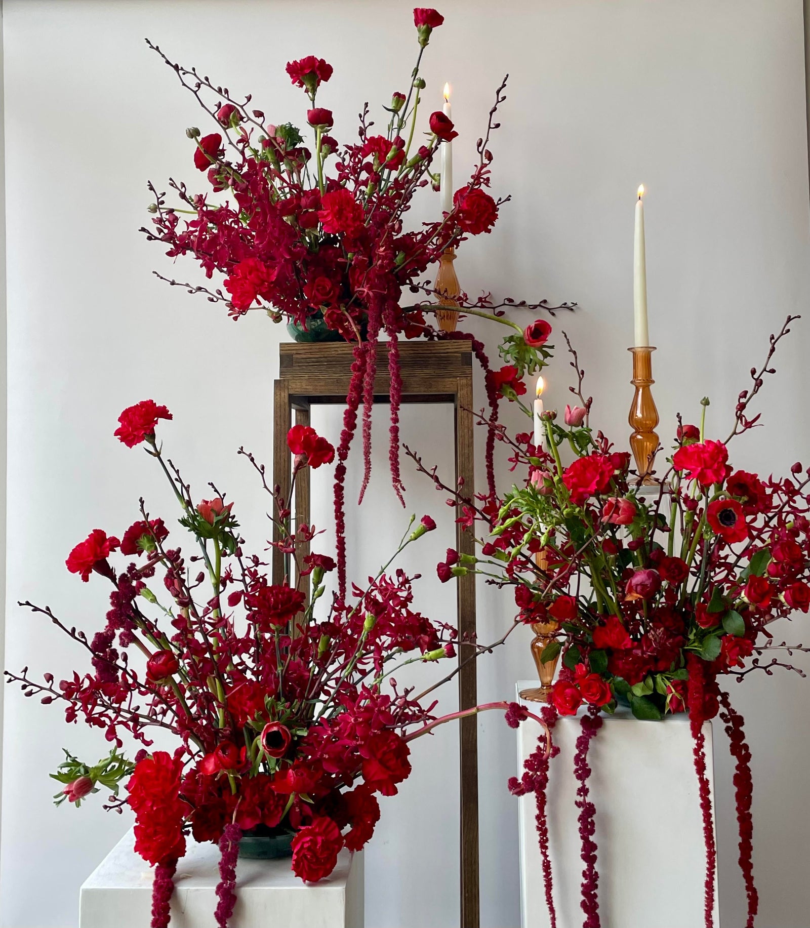 Trio of red on red arrangements on various pedestals by Sprout Home
