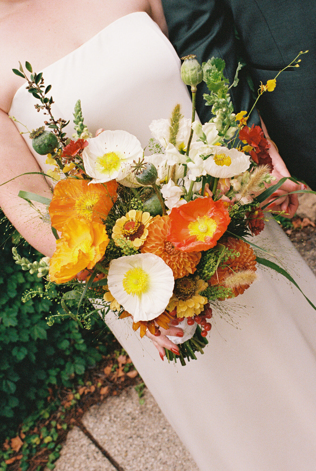 Bouquet of flowers featuring California Poppies and created by Sprout Home, held by the bride, with a focus on vibrant orange and white flowers. ©Unabridged Photo