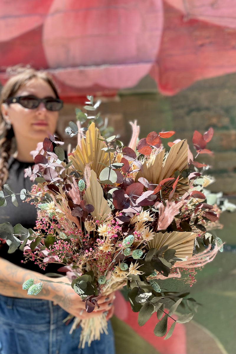 Sprout Home 'Faerie' preserved arrangement being held in front of a graffiti wall by a Sprout Home floral associate. 