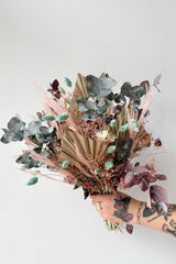 'Faerie' preserved arrangement by sprout home being held against a white wall showing the pastel elements.