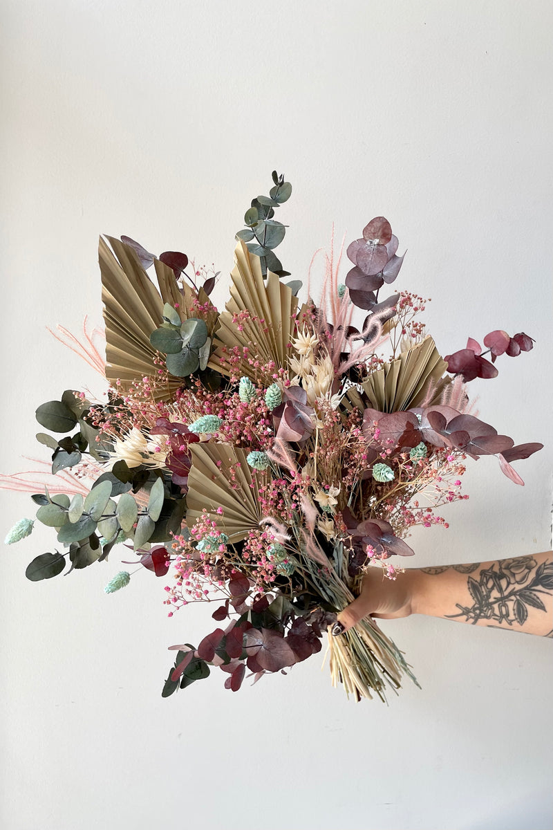 'Faerie' arrangement of shades of beige, pink and mint being held against white wall created by Sprout Home. 