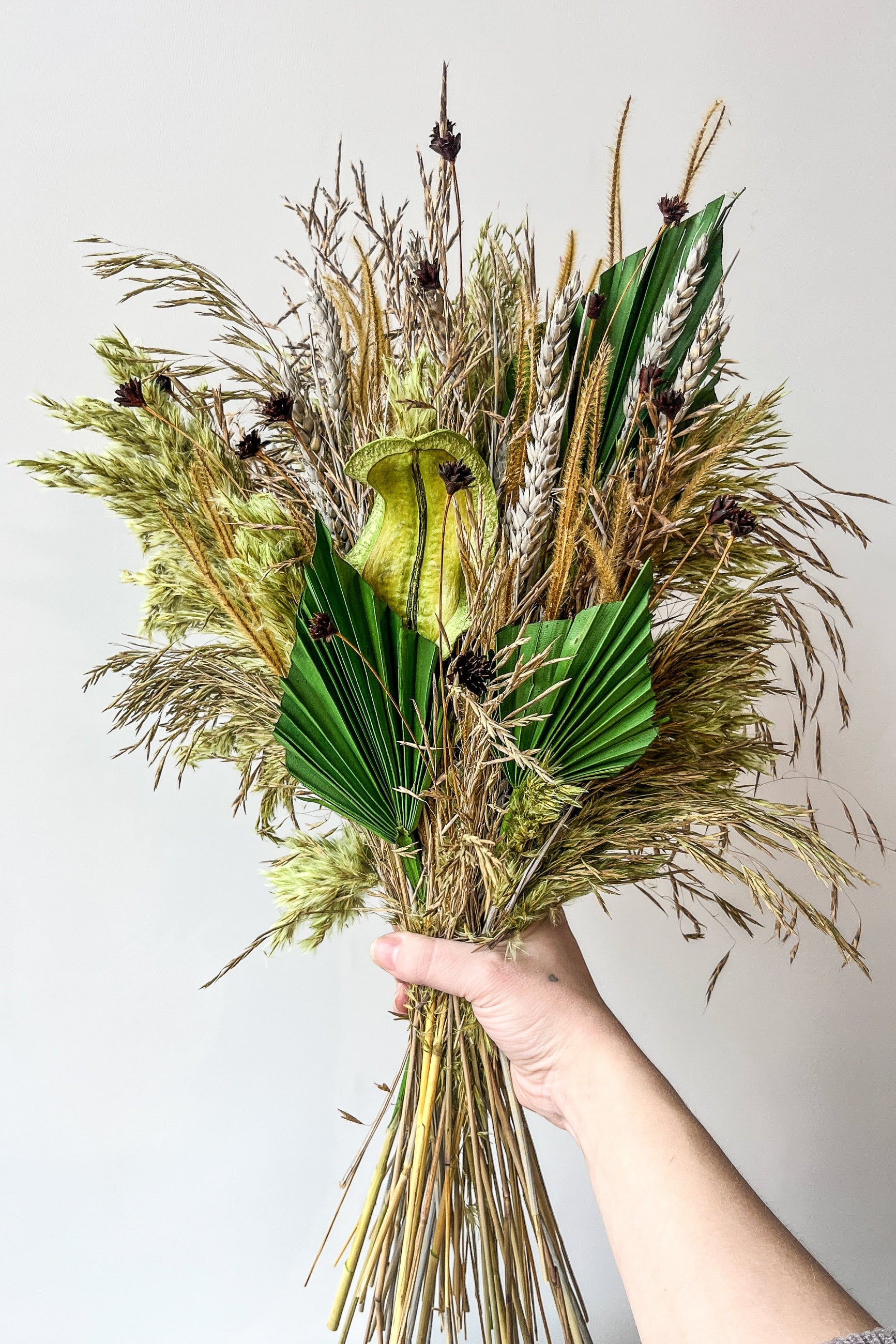 Sprout Home's preserved floral arrangement Flora Borealis being held in hand showing off the shades of brown and green ©Sprout Home #size_$160