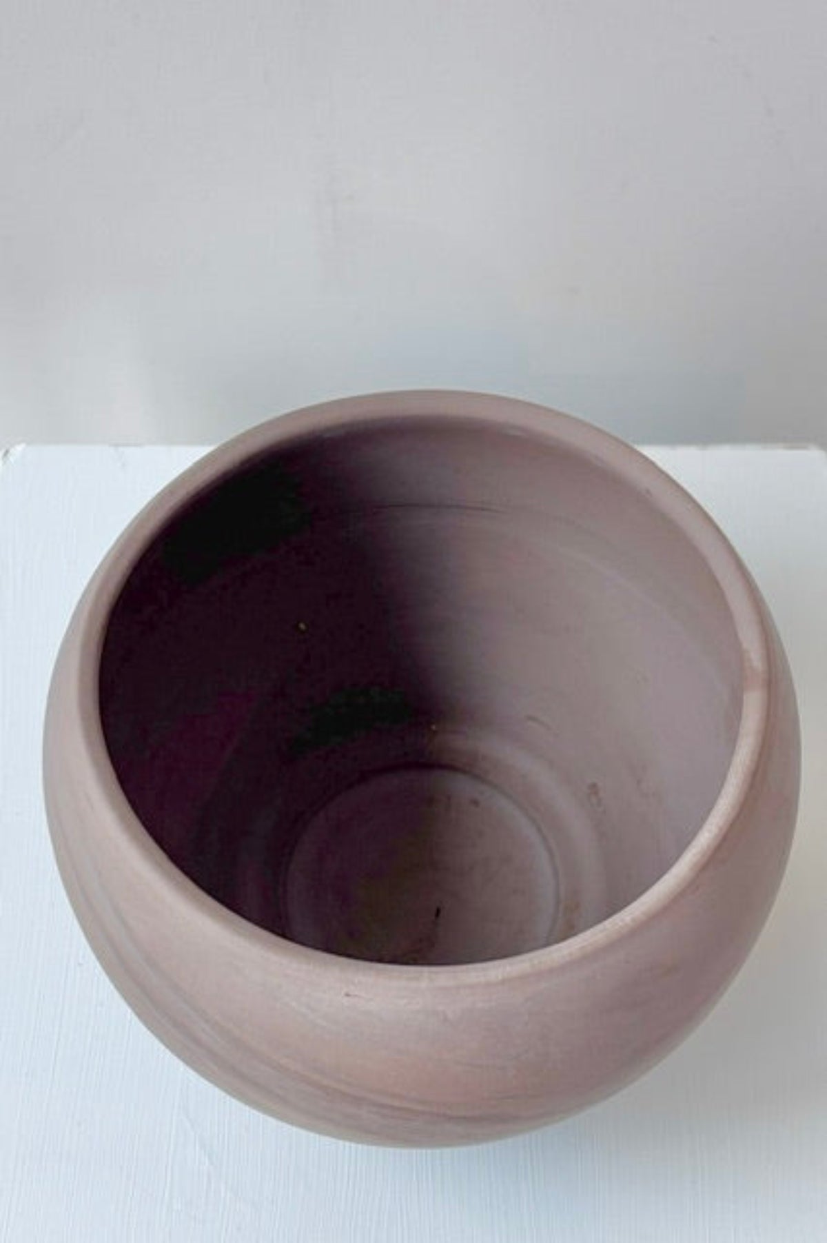 Interior of a sphere shaped grey/brown planter against a white background. Does not have a drainage hole. ©Sprout Home