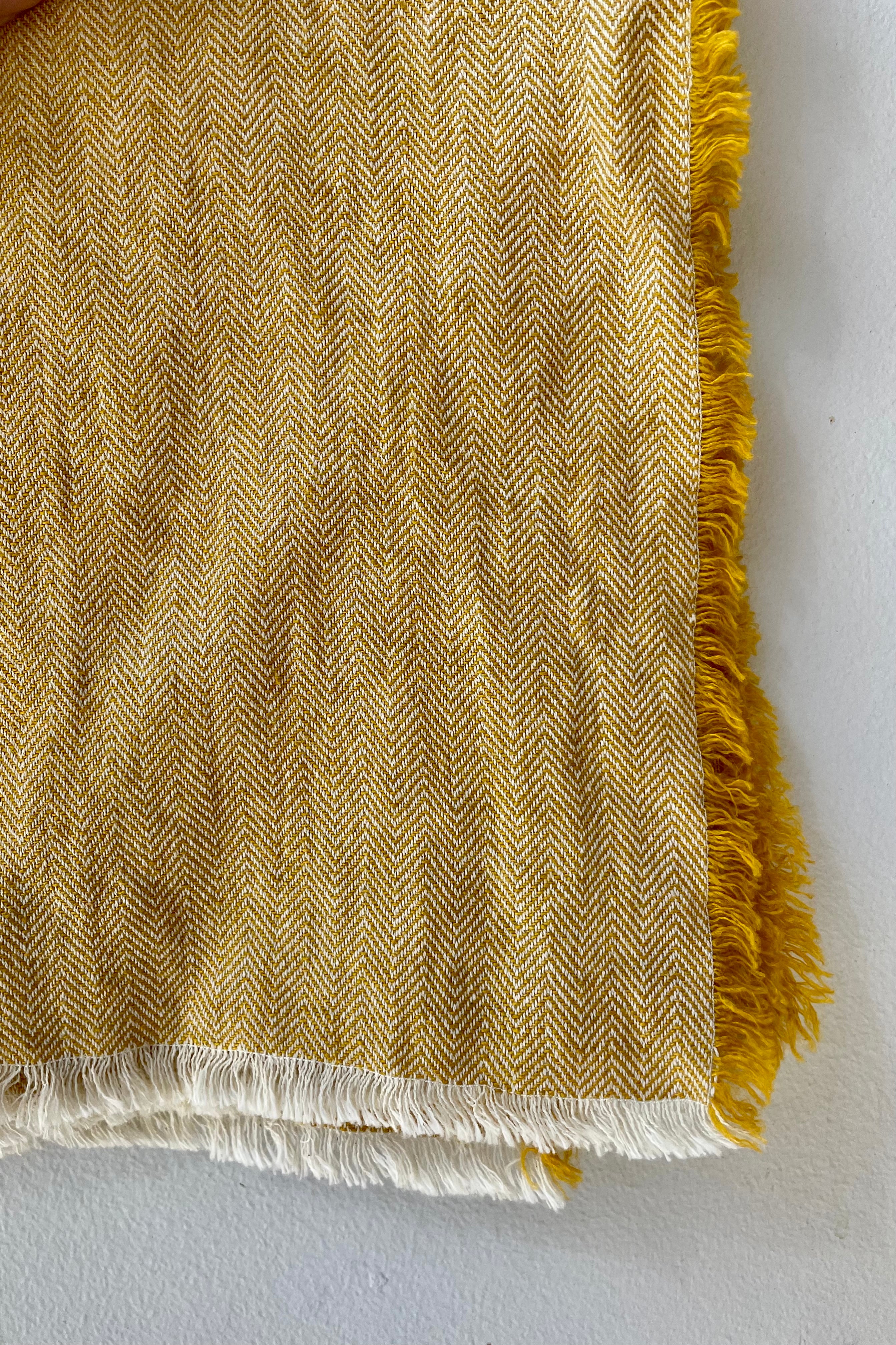 Close detail Photo of a Herrinbone pattern Mustard colored fringed napkin