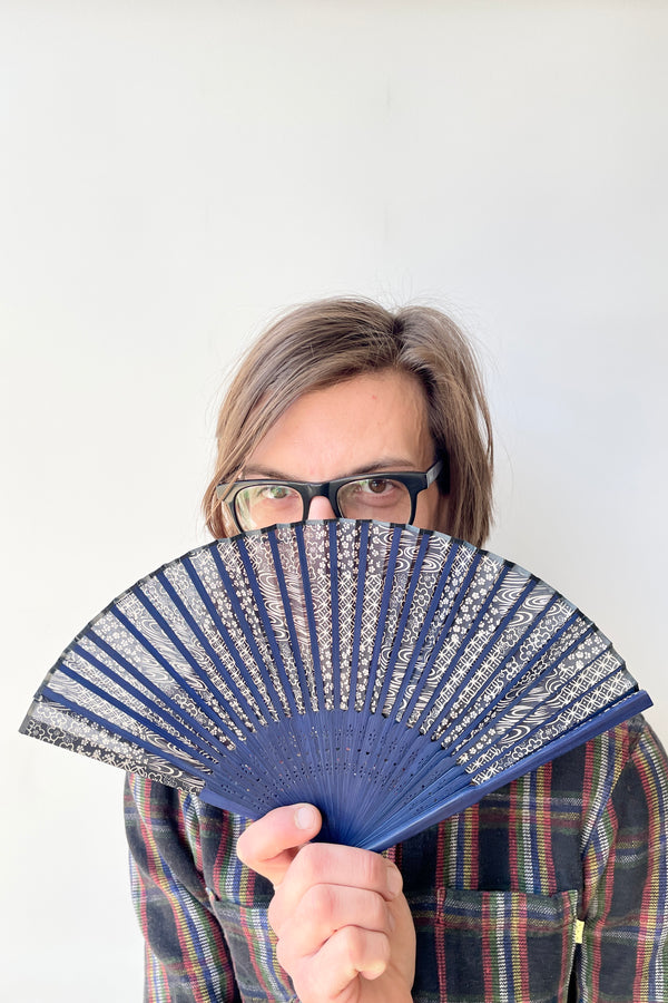 Sprout Home staff member holding a silk fan blue swirl pattern with blue bamboo at Sprout Home. 