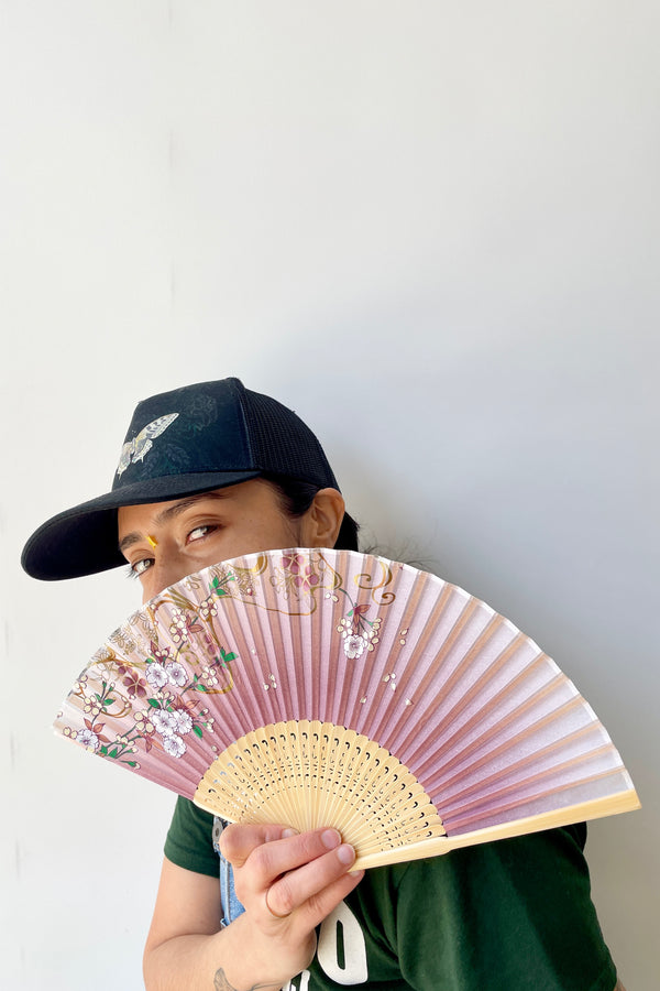 Silk fan cherry blossom pattern being held by a Sprout Home staff member. 