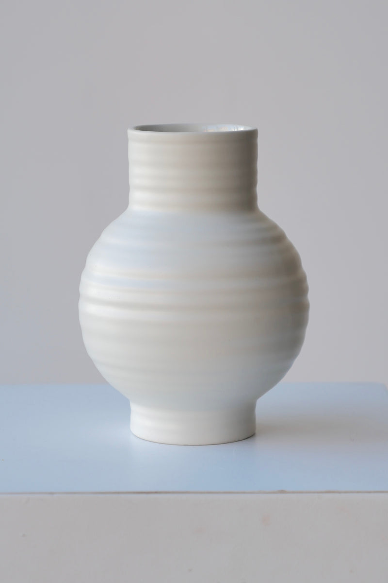 The Small Essential Bone Ceramic vase by Hawkins against a white wall. 