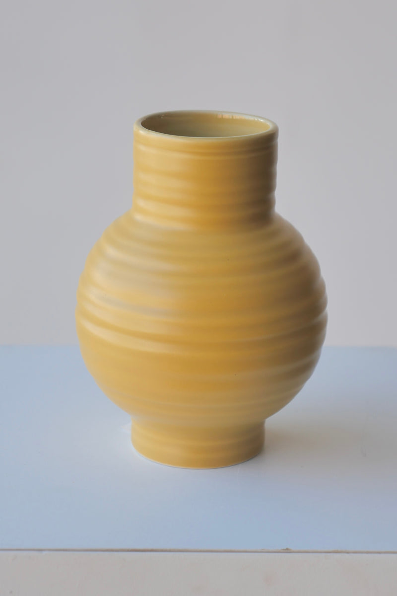 A single Small Mustard Essential Vase by Hawkins NY against white. 