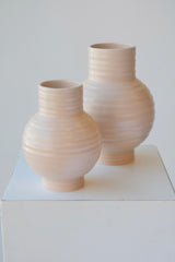A par of large and small Essential blush vases on white. 