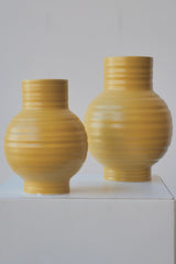 A pair of Mustard Essential Vases by Hawkins NY against a white wall. 