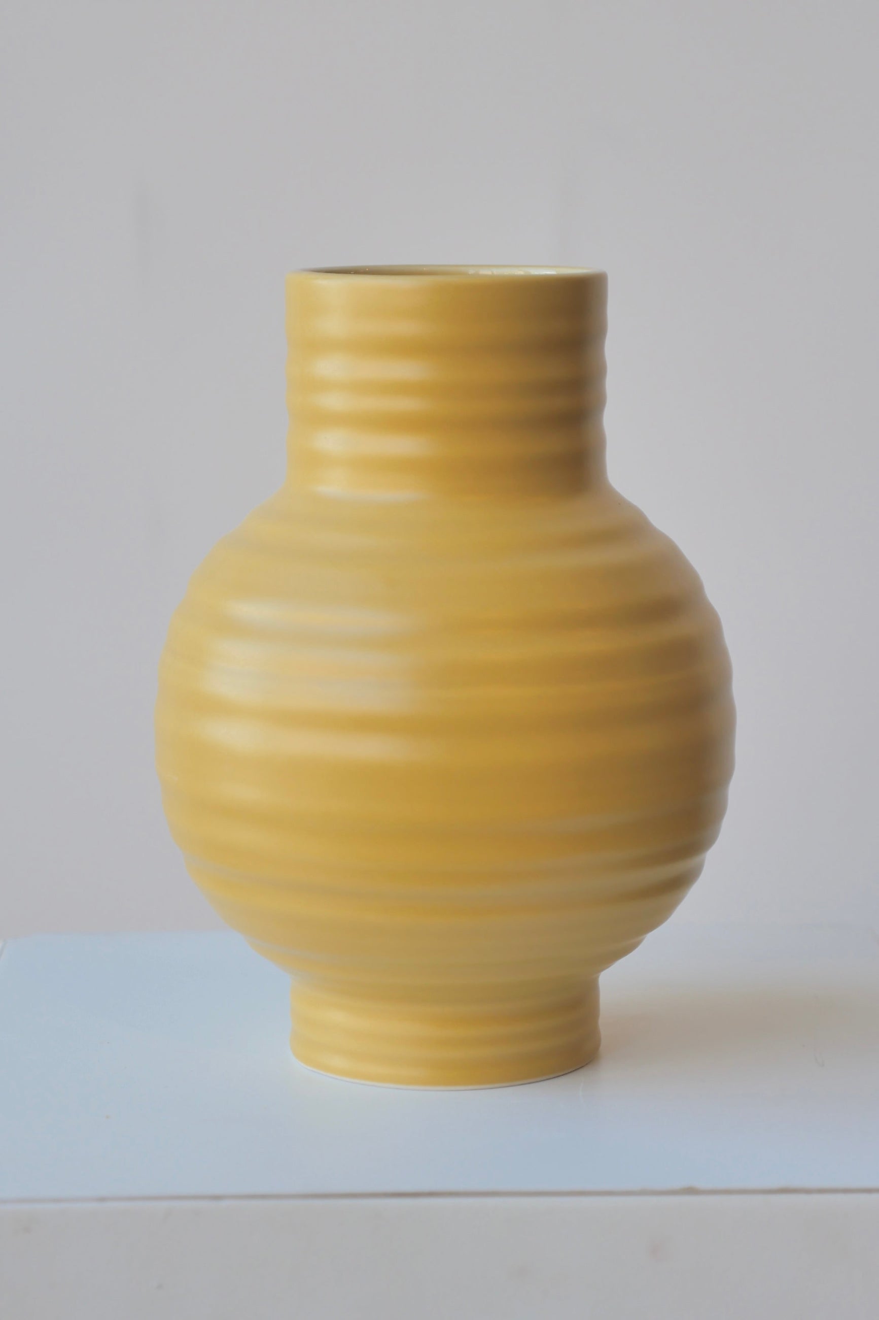 Mustard colored Essential vase by Hawkins at eye level against a white background.  ©Sprout Home