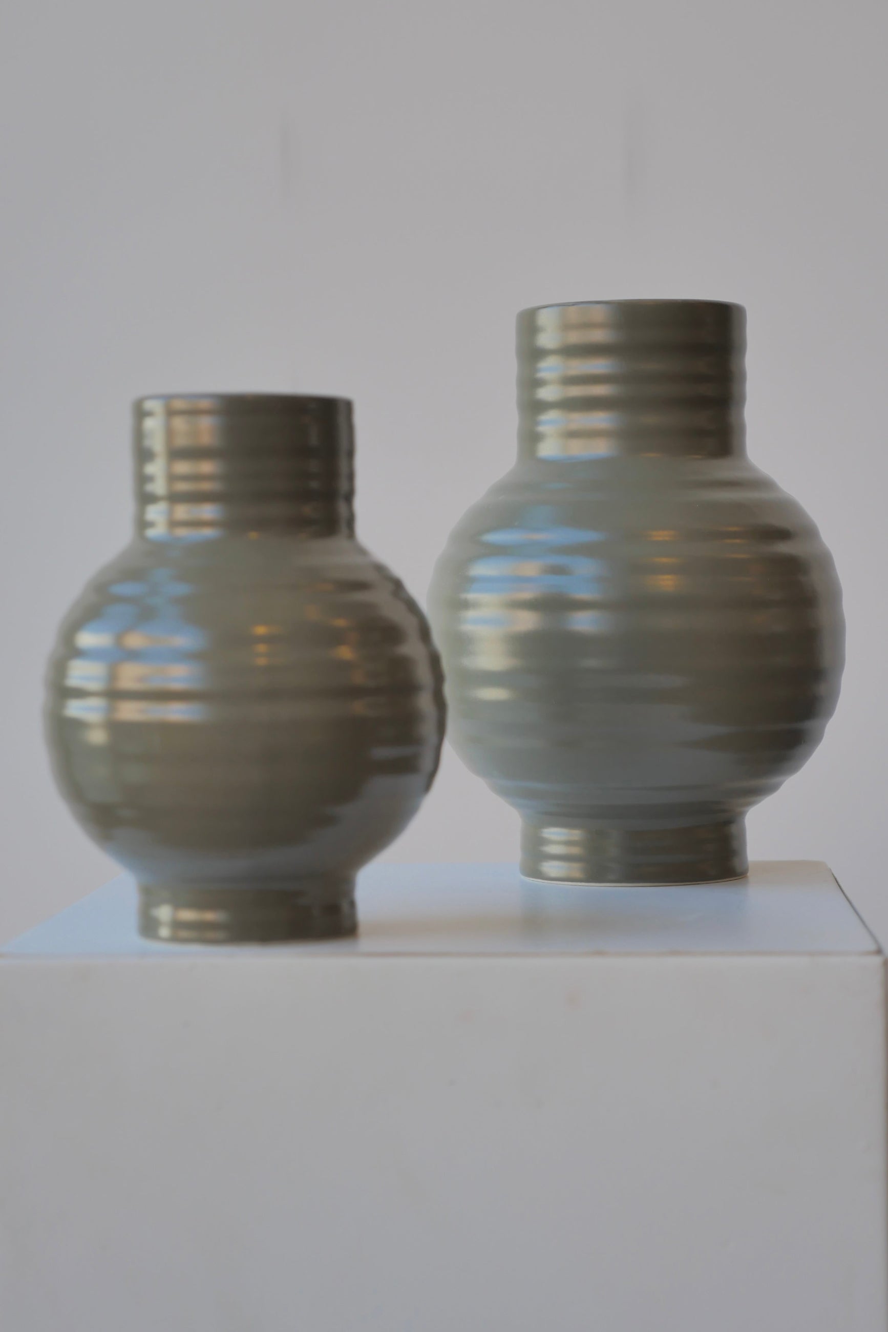 A pair of Olive colored Essential Vases at eye level with the smaller one in front.  ©Sprout Home