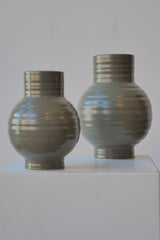 A pair of Olive colored Essential Vases at eye level with the smaller one in front.