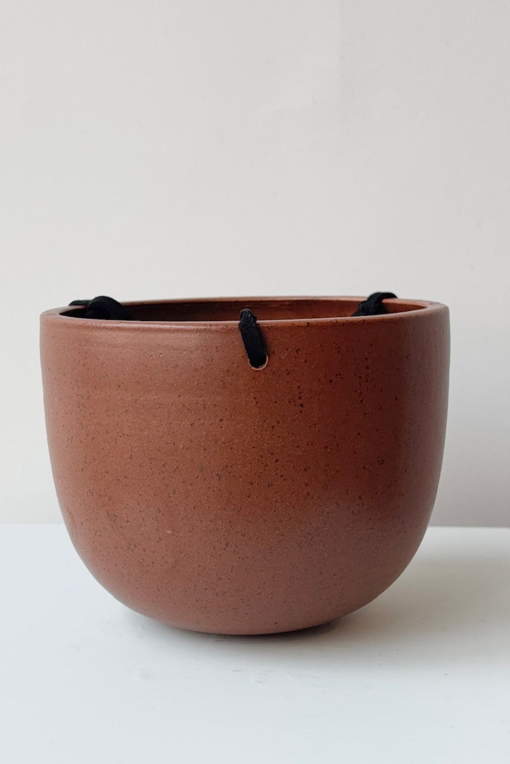 Brown ceramic pot with black speckles and a black cord on a white surface and light gray background ©Sprout Home