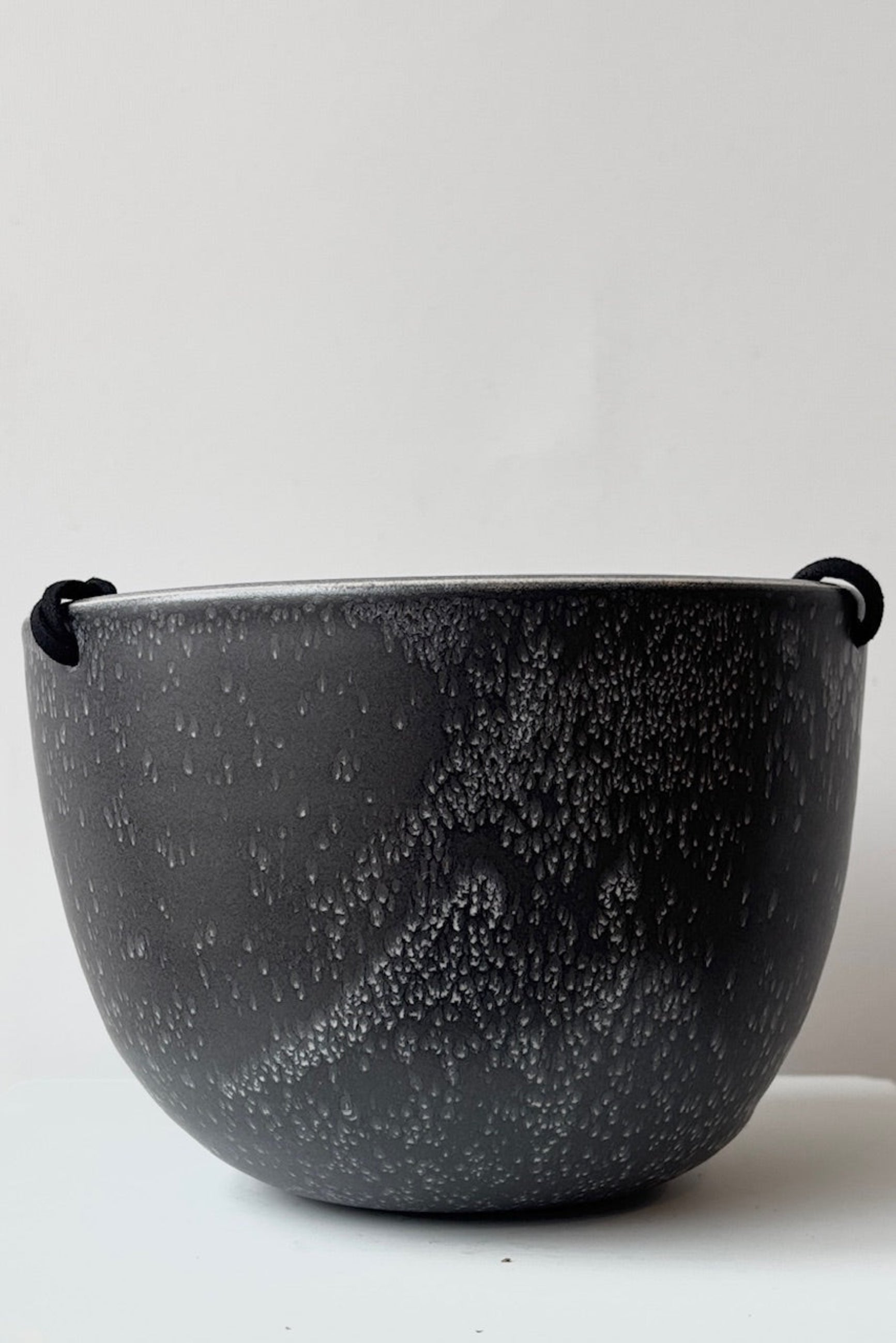 Black speckled ceramic hanging planter  with a black cord on a white background ©Sprout Home