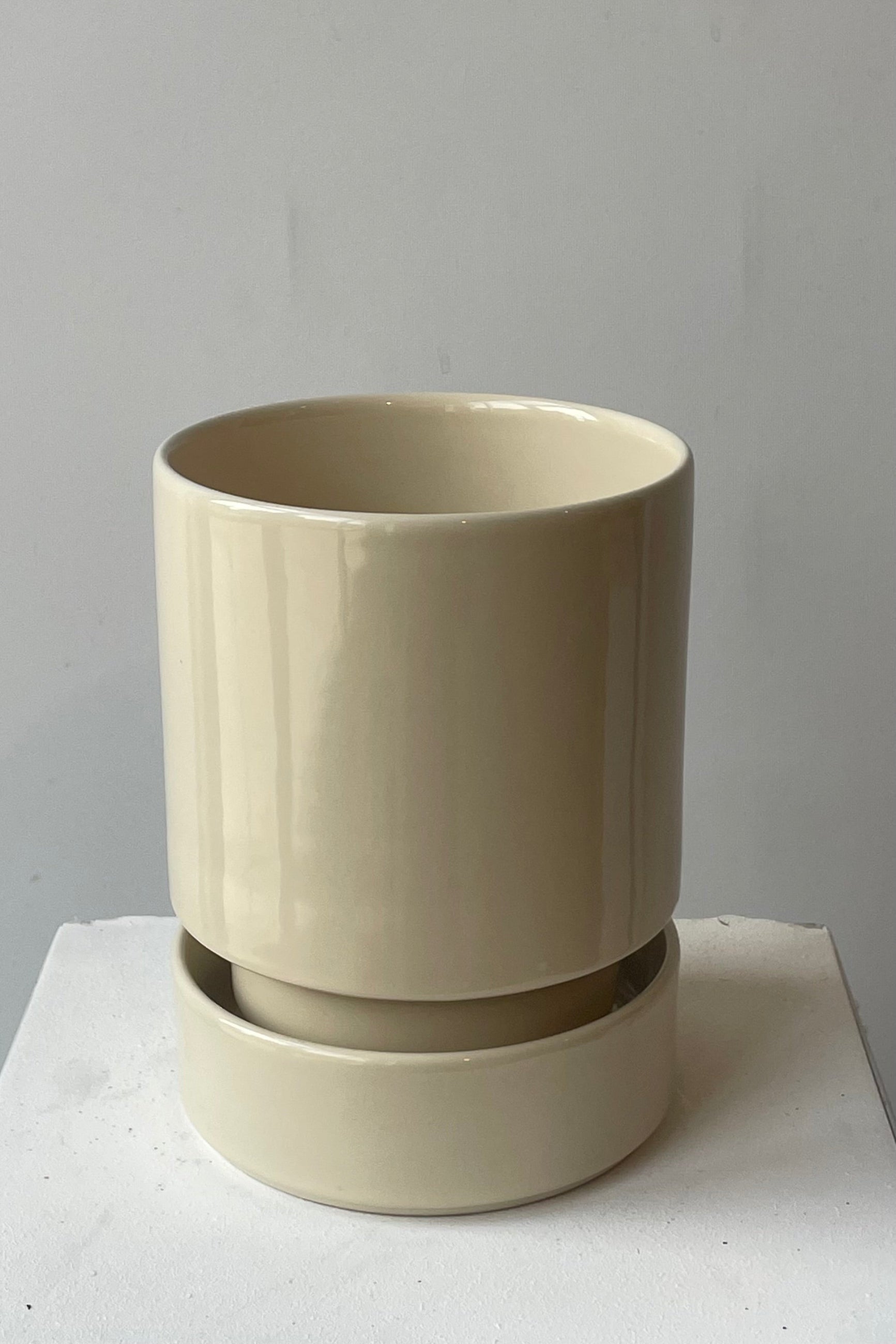 A beige ceramic pot and saucer in a white room. Sandstone Hoff pot by Bergs Potter shown from above. ©Sprout Home