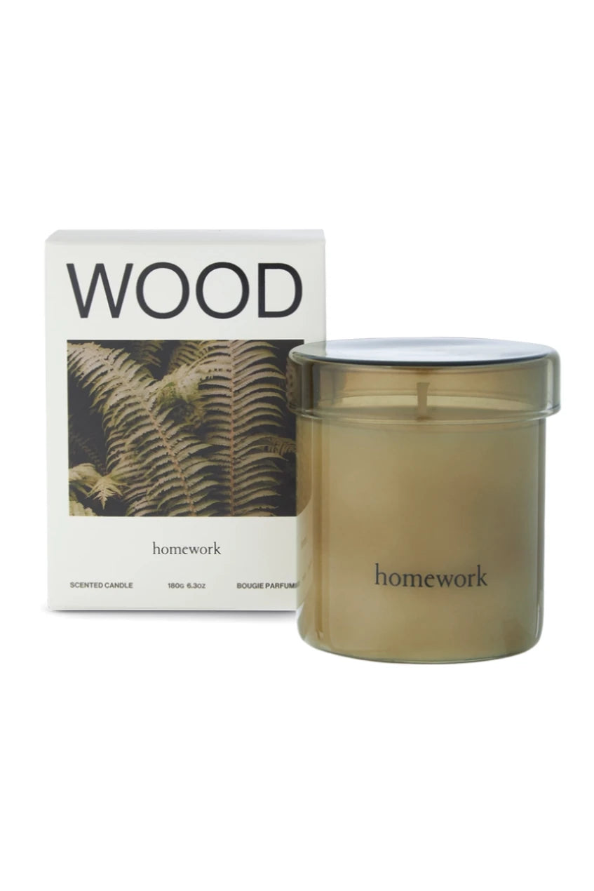 Wood candle in glass outside of its packaging and sitting in front of its box by Homework. 