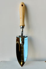 Hand trowel etched with markings in one inch increments with wooden handle against white background