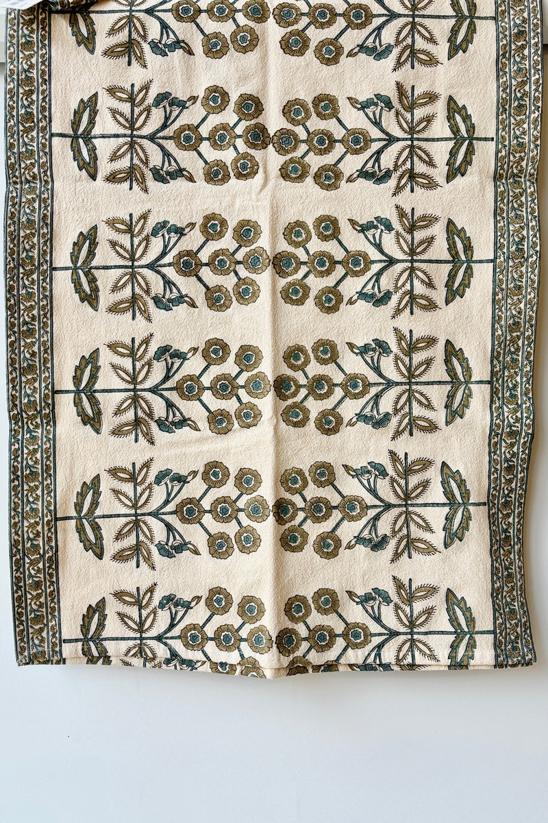 One hundred percent cotton table runner with a teal and gold floral motif arranged in a symmetrical pattern with a border of smaller floral patterns at the edges. 