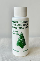 Keeps It Green Christmas tree food in a white bottle with green text and image of a  pine tree against white background