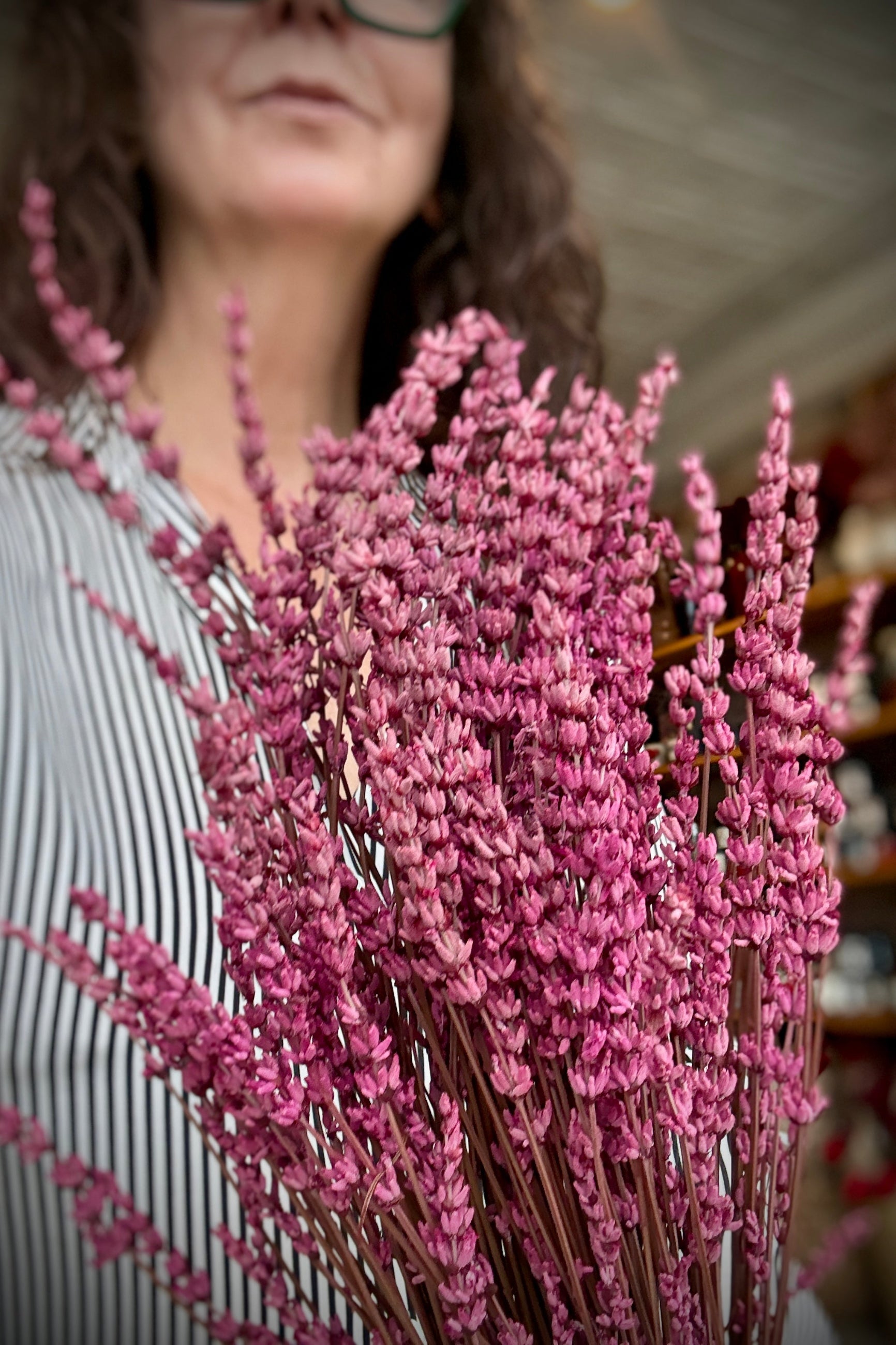 Person holding a bundle of Fuchsia preserved lavender flowers with a blurred background ©Sprout Home