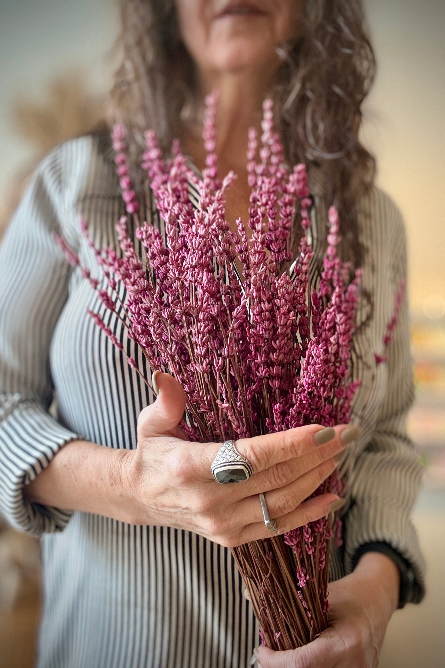Person holding a bundle of Fuchsia Lavender flowers with a blurred background ©Sprout Home