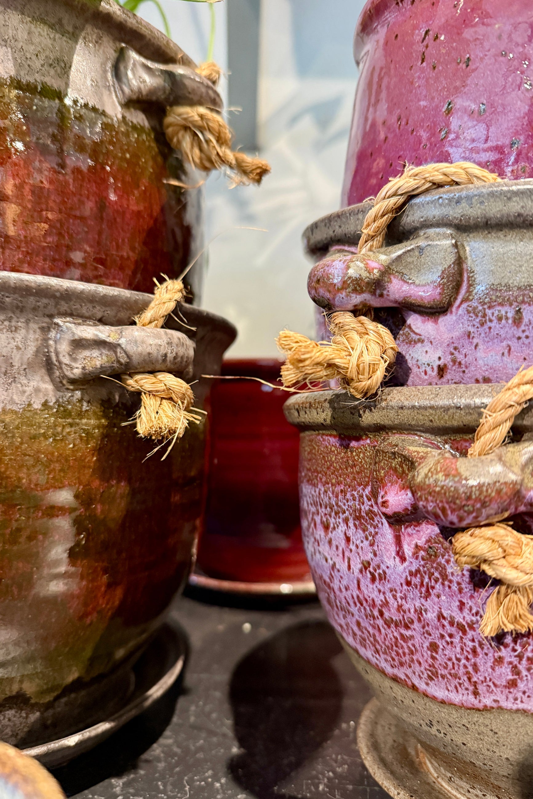Close-up of ceramic hanging pots with rope handles by Bruning Pottery on a reflective surface. ©Sprout Home