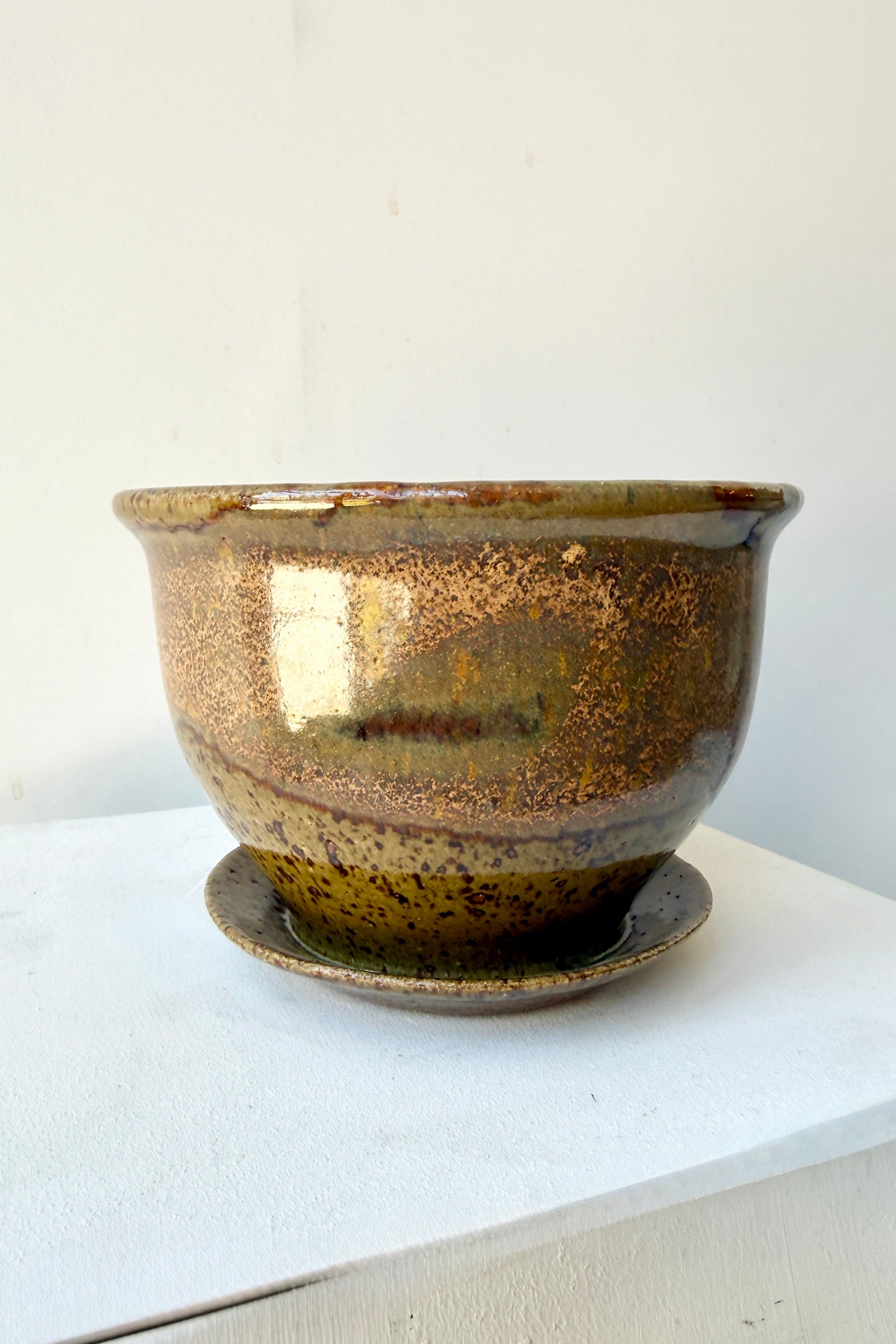 Ceramic 4" Bruning pot in an Army Green with Yellow speckled glaze on a stone surface. ©Sprout Home