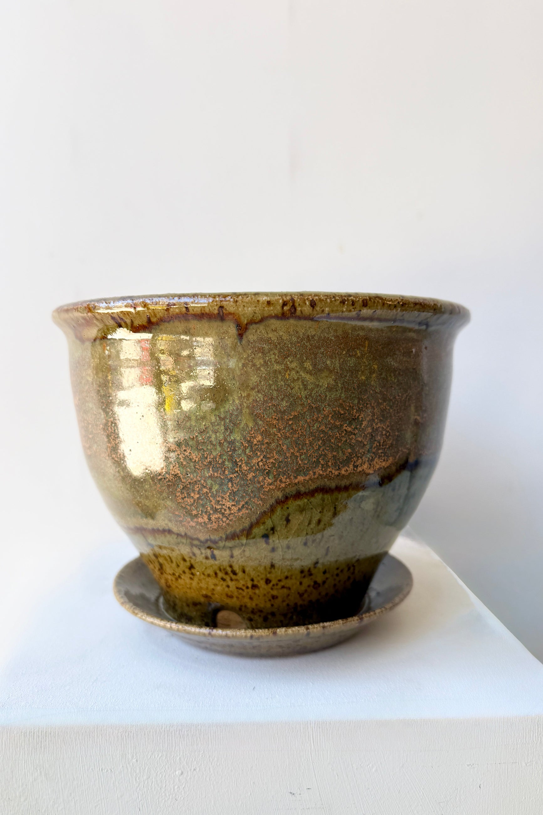 Ceramic 6" Bruning pot in an Army Green with Yellow speckled glaze on a stone surface. ©Sprout Home