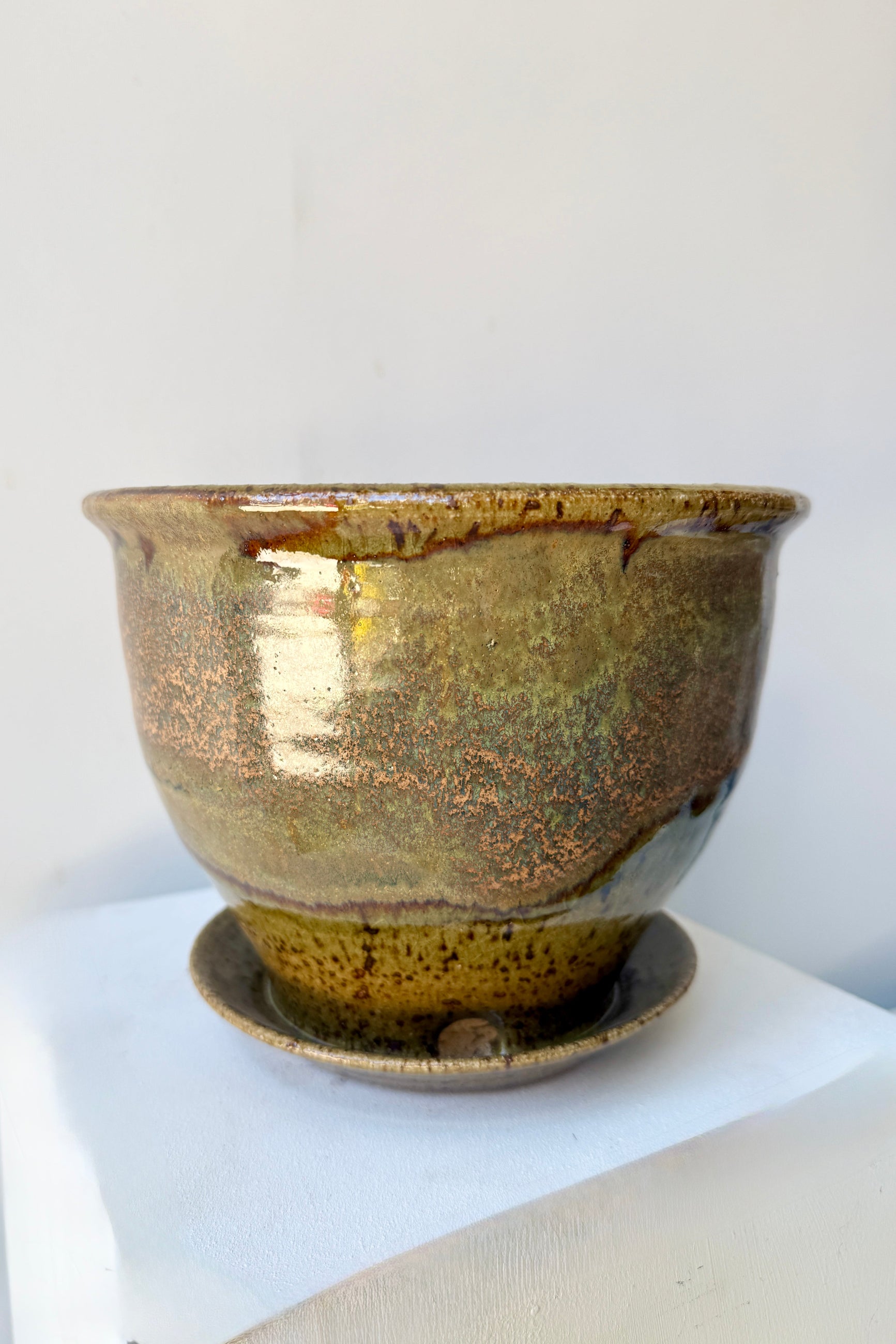 Ceramic 6" Bruning pot in an Army Green with Yellow speckled glaze on a stone surface. ©Sprout Home