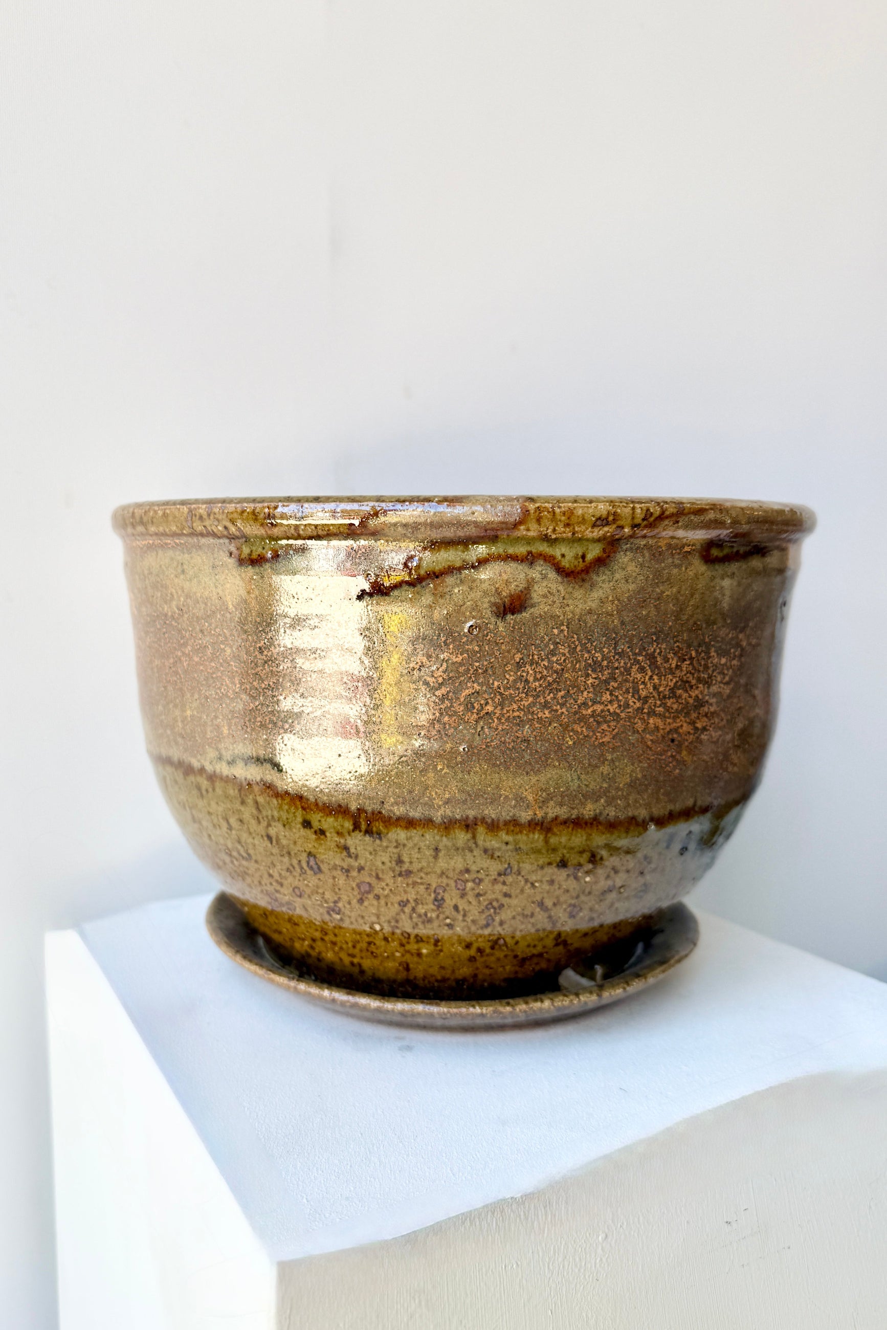 Ceramic 8" Bruning pot in an Army Green with Yellow speckled glaze on a stone surface. ©Sprout Home