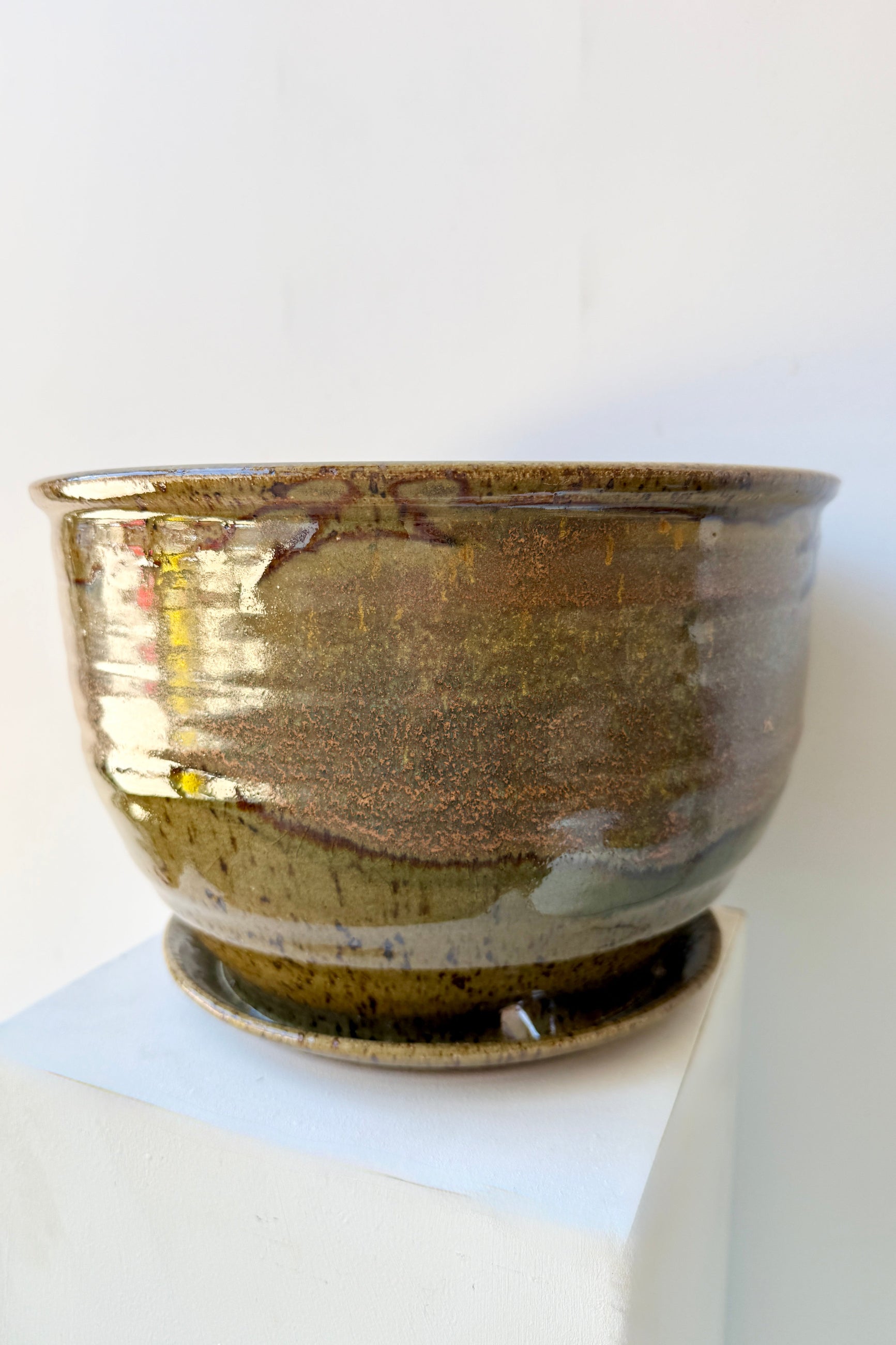 Ceramic 10" Bruning pot in an Army Green with Yellow speckled glaze on a stone surface. ©Sprout Home