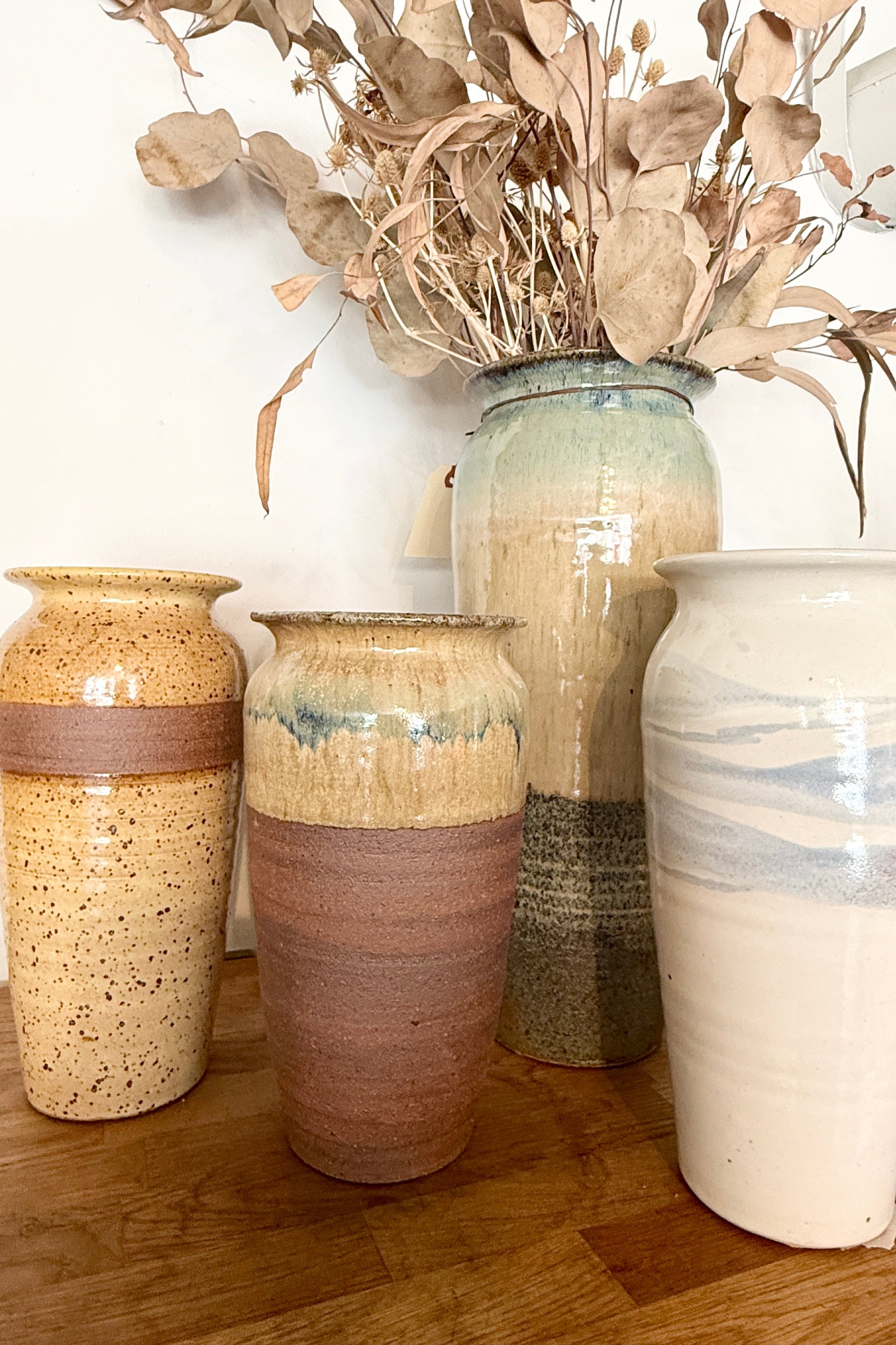 Set of ceramic Bruning Pottery vases with textured finishes on a wooden shelf at Sprout Home Floral ©Sprout Home