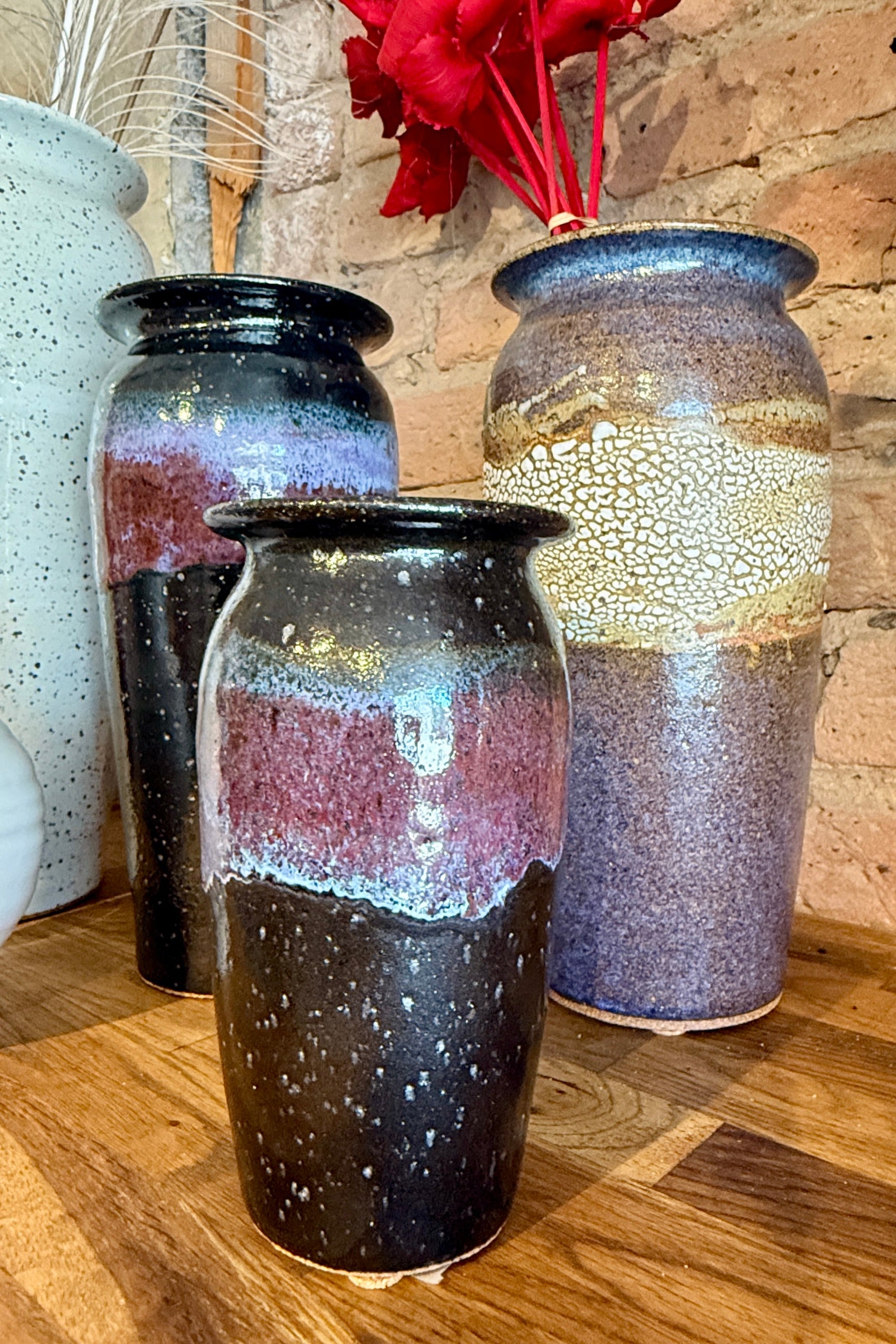 Three Judy Brunning ceramic vases with unique glaze patterns on a wooden surface at Sprout Home Floral ©Sprout Home