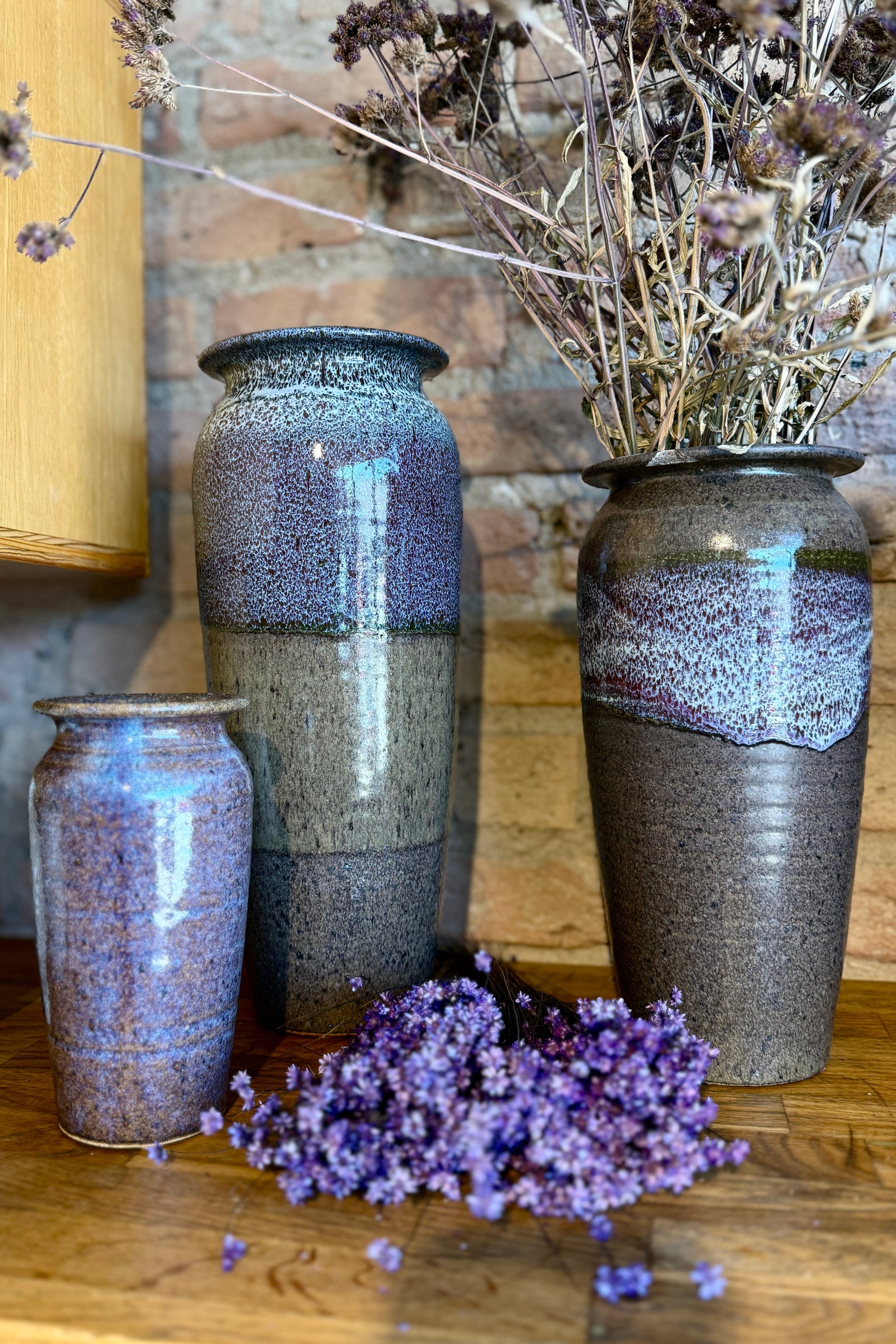 Set of three Bruning Pottery ceramic vases with textured purple and gray glaze on a wooden surface. with preserved flowers at Sprout Home Floral ˙©Sprout Home