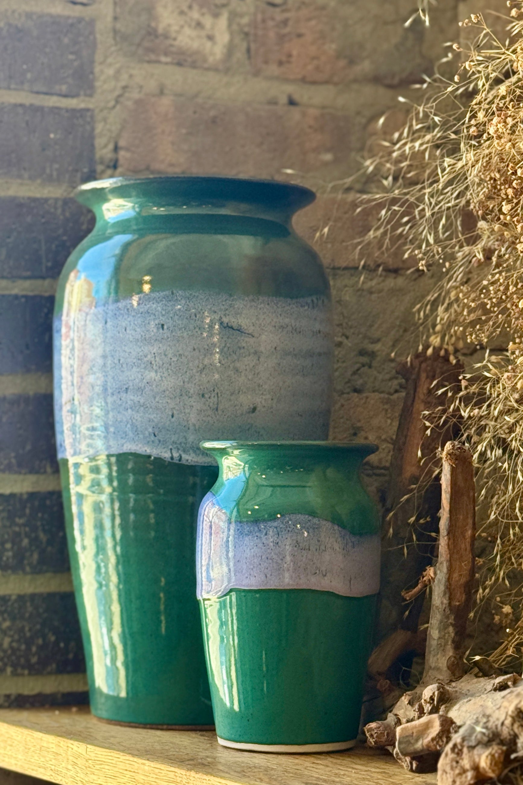 Two Bruning Pottery green ceramic vases with white stripes on a display shelf at Sprout Home Floral ©Sprout Home