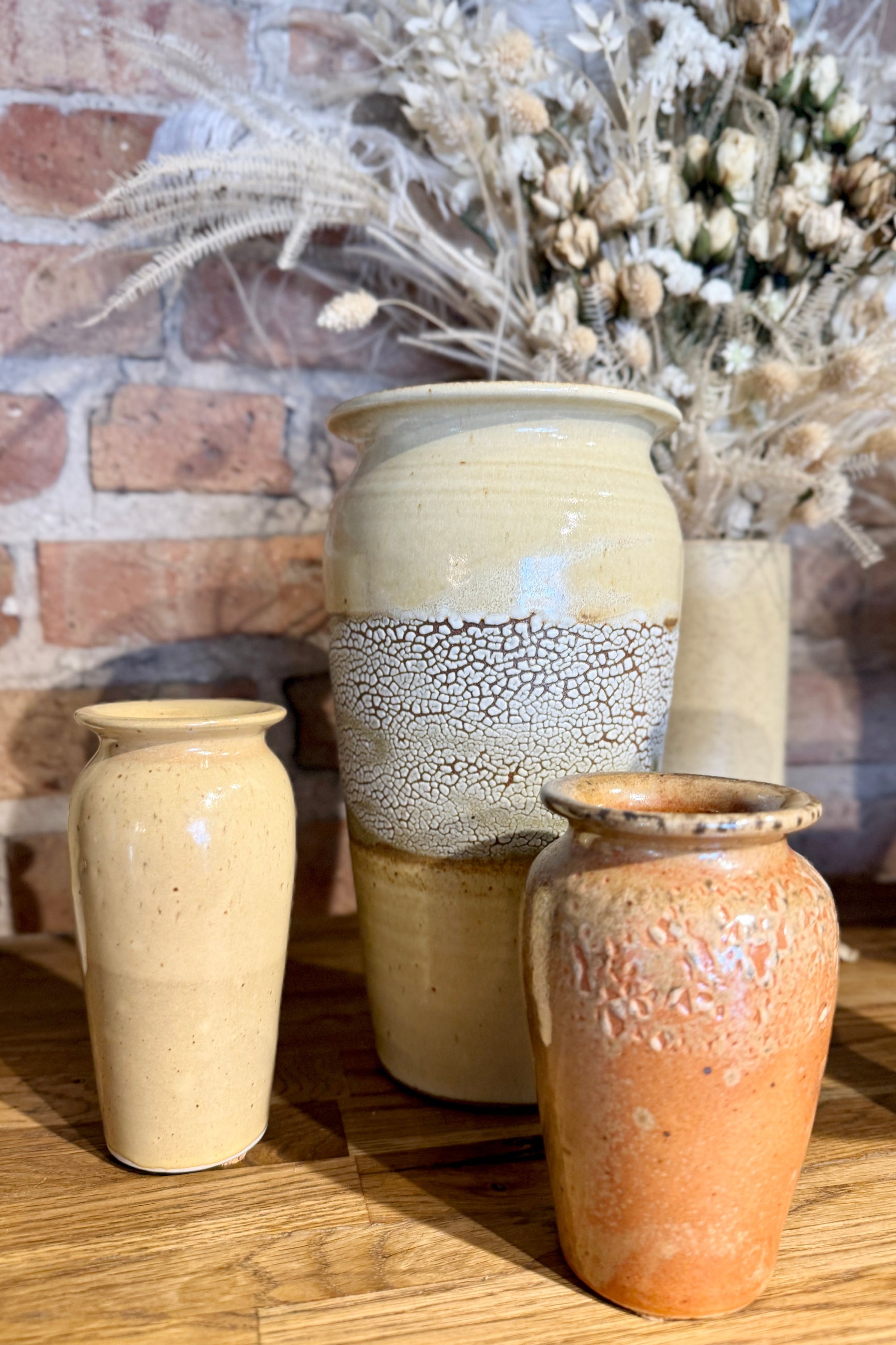 Bruning Pottery Vases, a large one with a white crackle glaze, and an warm orange small one in front on a wooden shelf at Sprout Home Floral ©Sprout Home