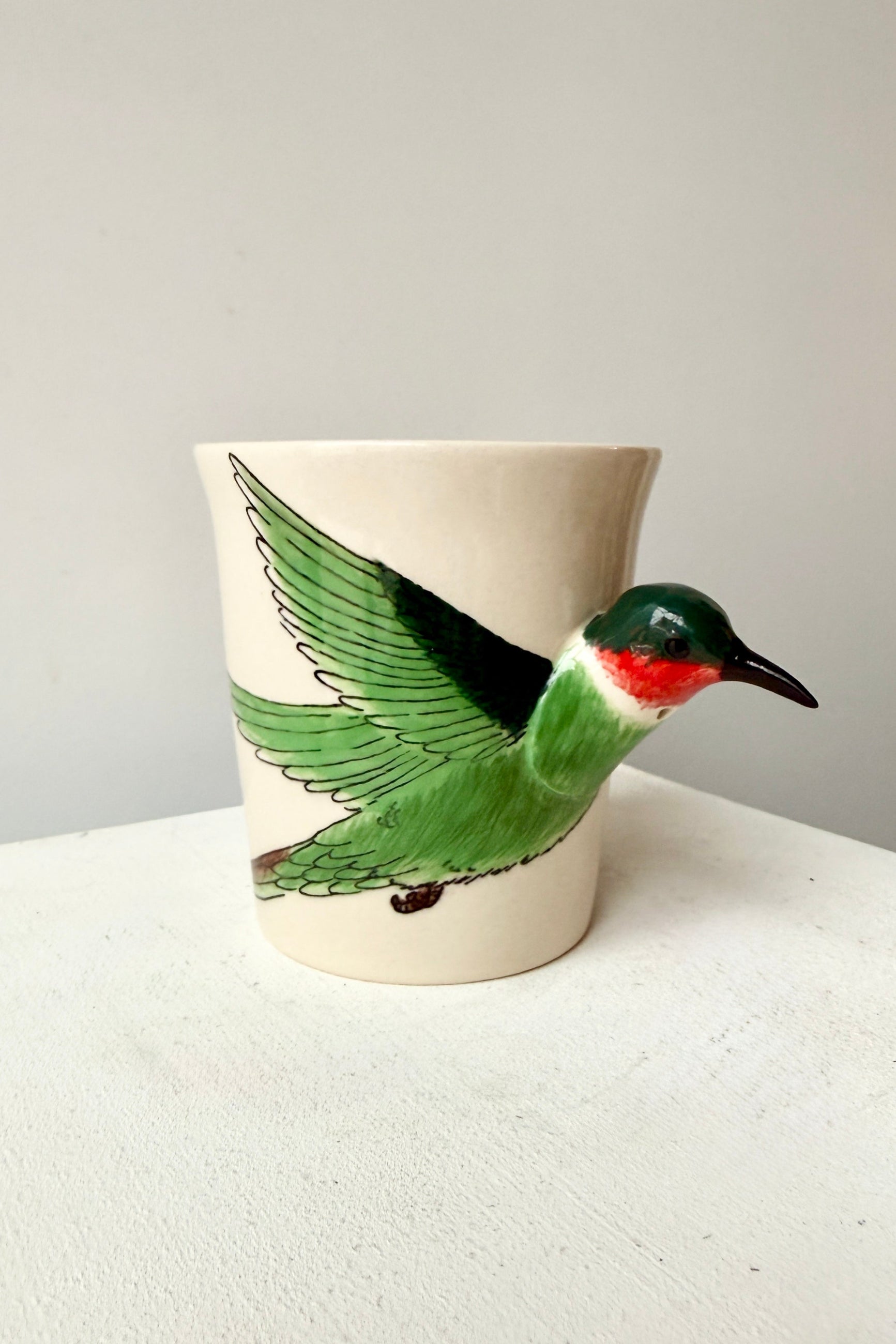Ceramic mug with a green bird design on a white surface ©Sprout Home