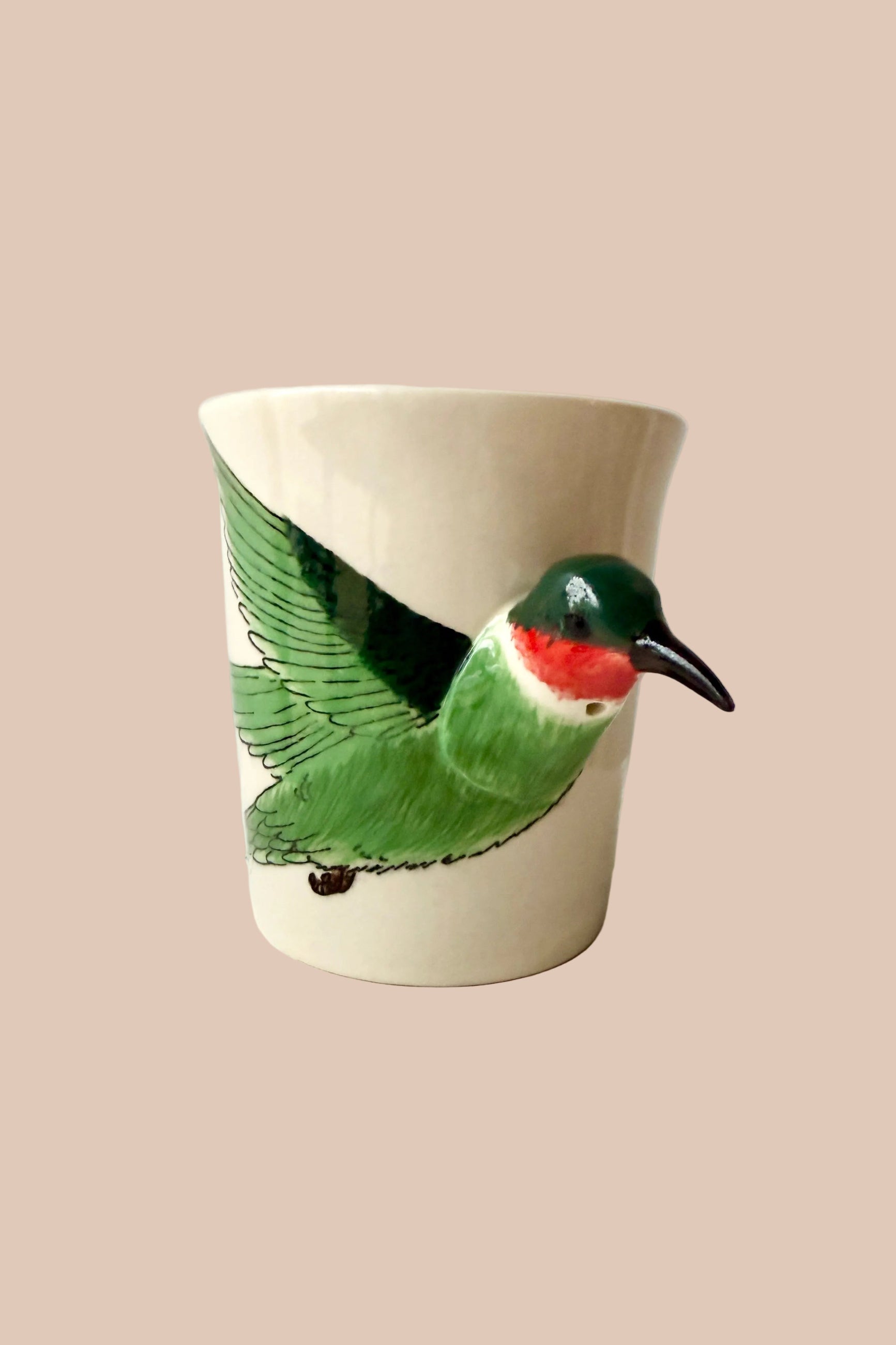 Ceramic mug with a green bird design on a white surface ©Sprout Home