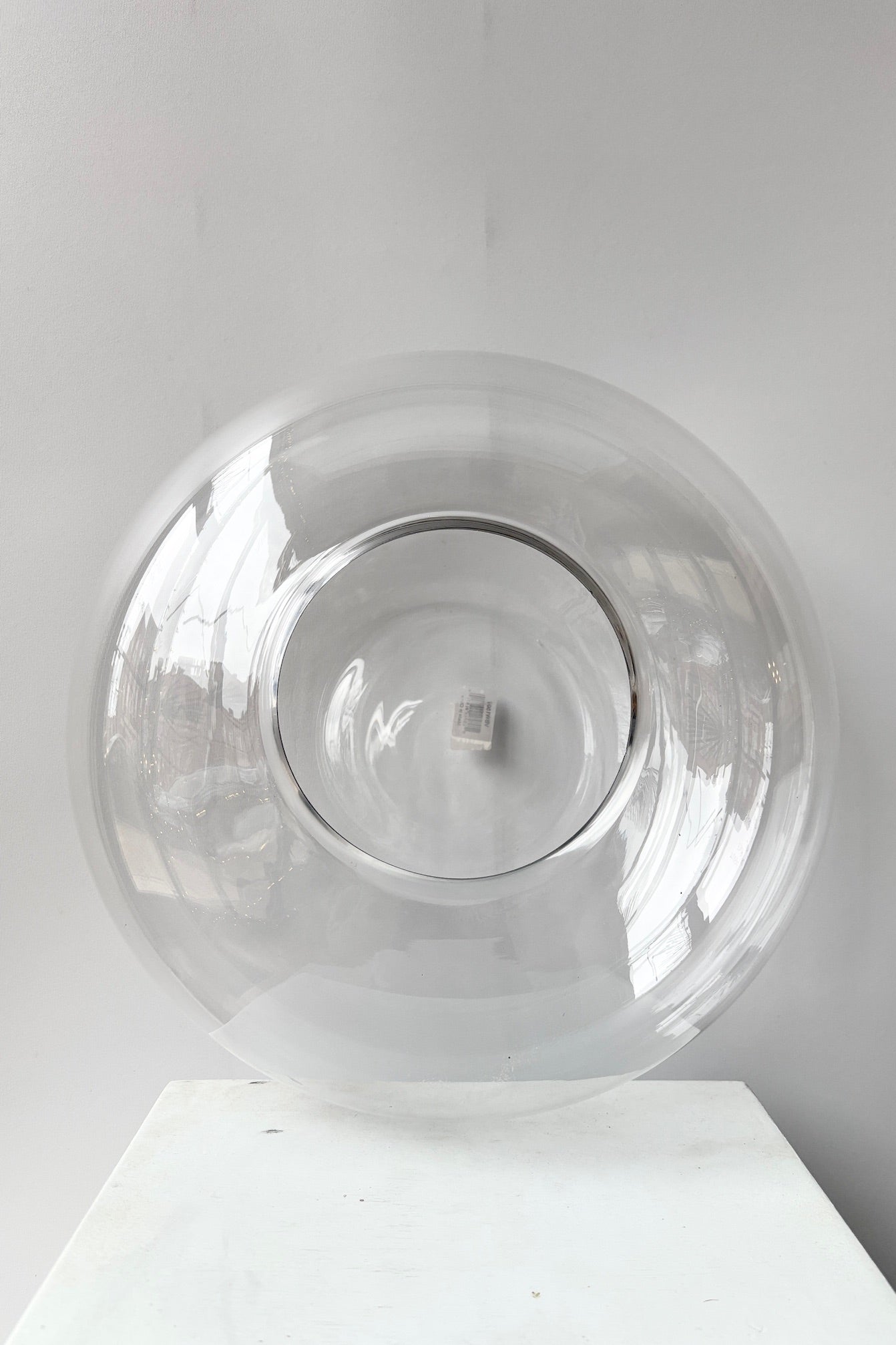 Clear glass Oblate terrarium on a grey surface against a white background. ©Sprout Home