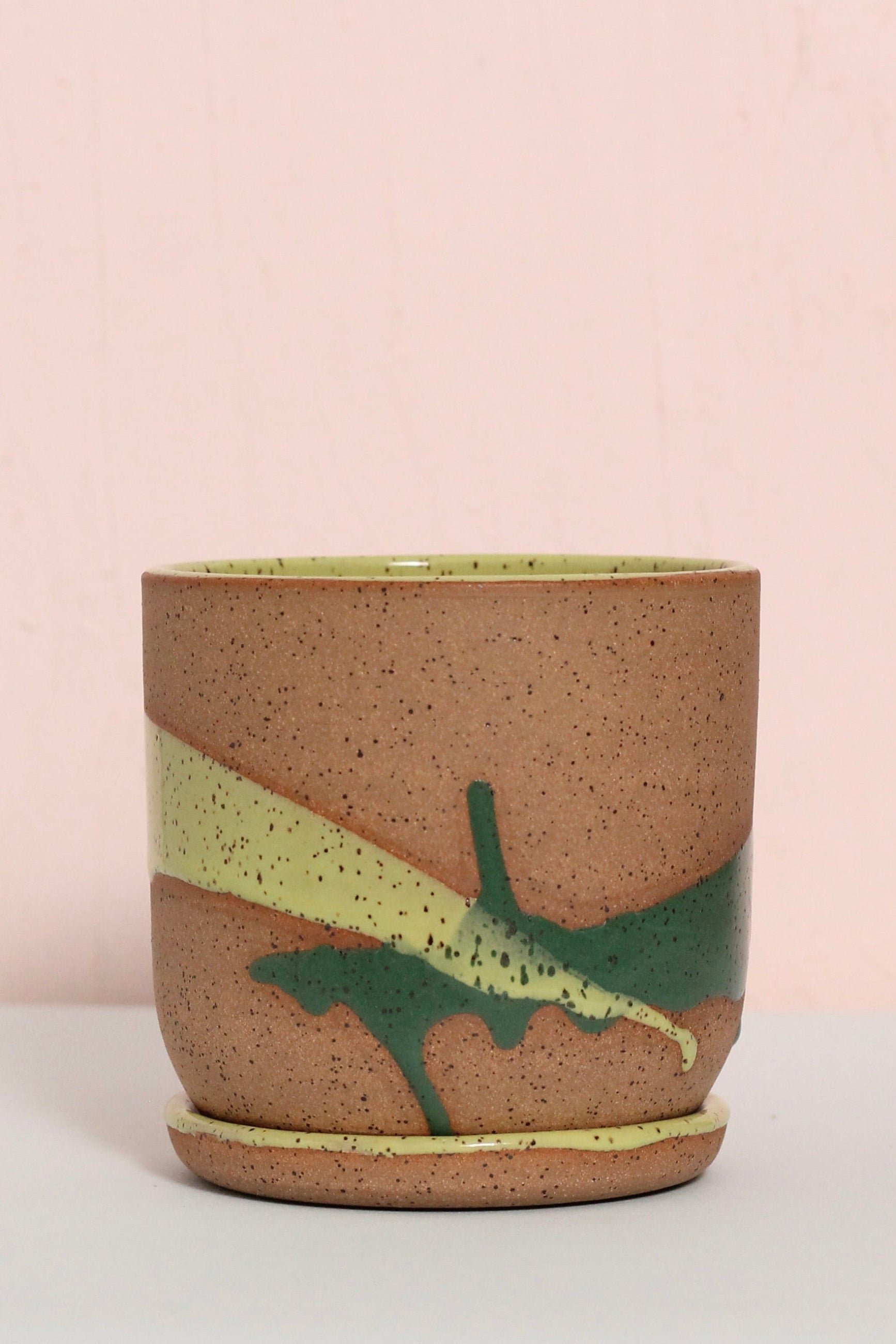 Ceramic cup with green and yellow design on a light pink background ©Christina Kosinski