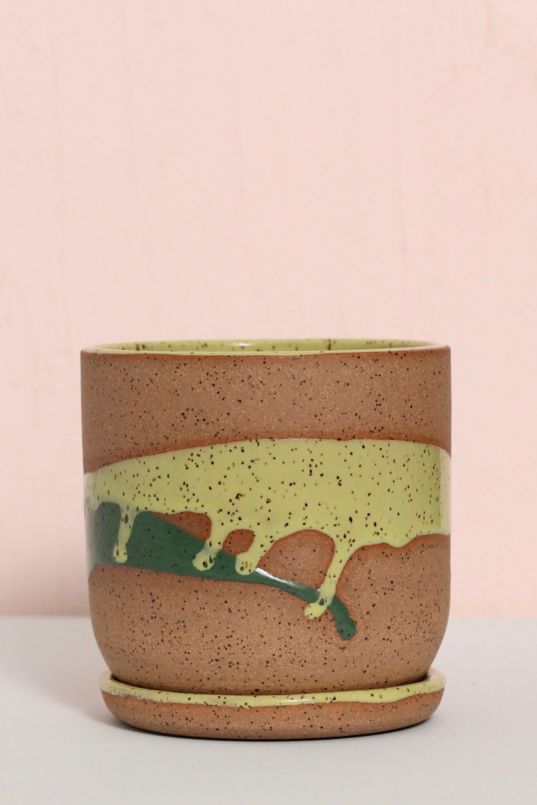 Ceramic cup with green and brown design on a light pink background ©Christinia Kosinski 