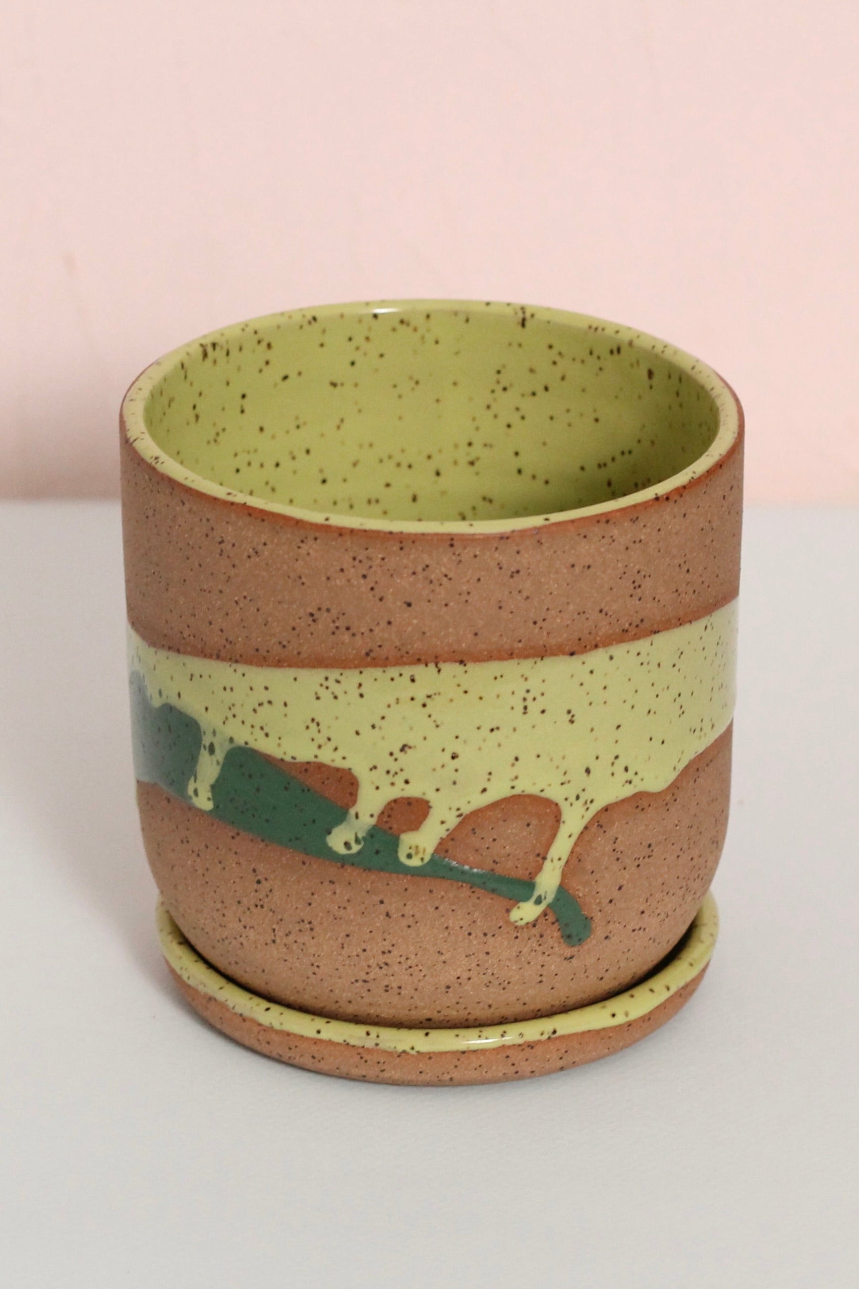Ceramic cup with speckled design on a light gray surface with a pink background ©Christina Kosinski