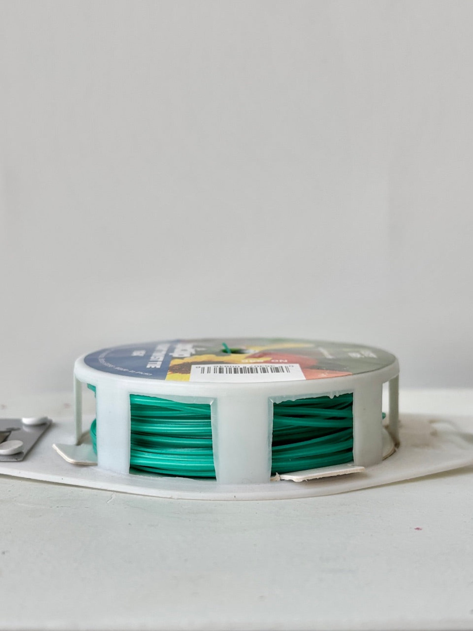 Spool of green plant twist tie against white background