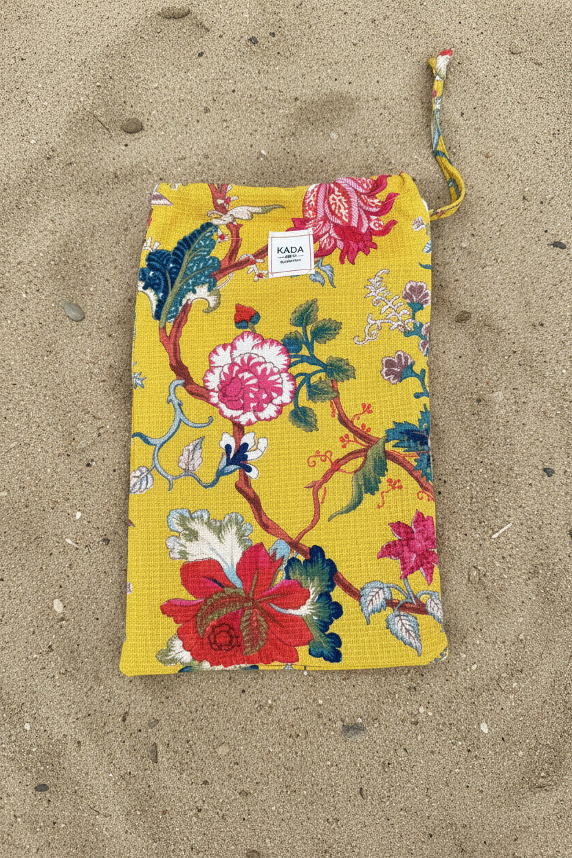 Waffle Cotton Beach Towel w/ Pouch Yellow Fleur sitting on sand ©Sprout Home