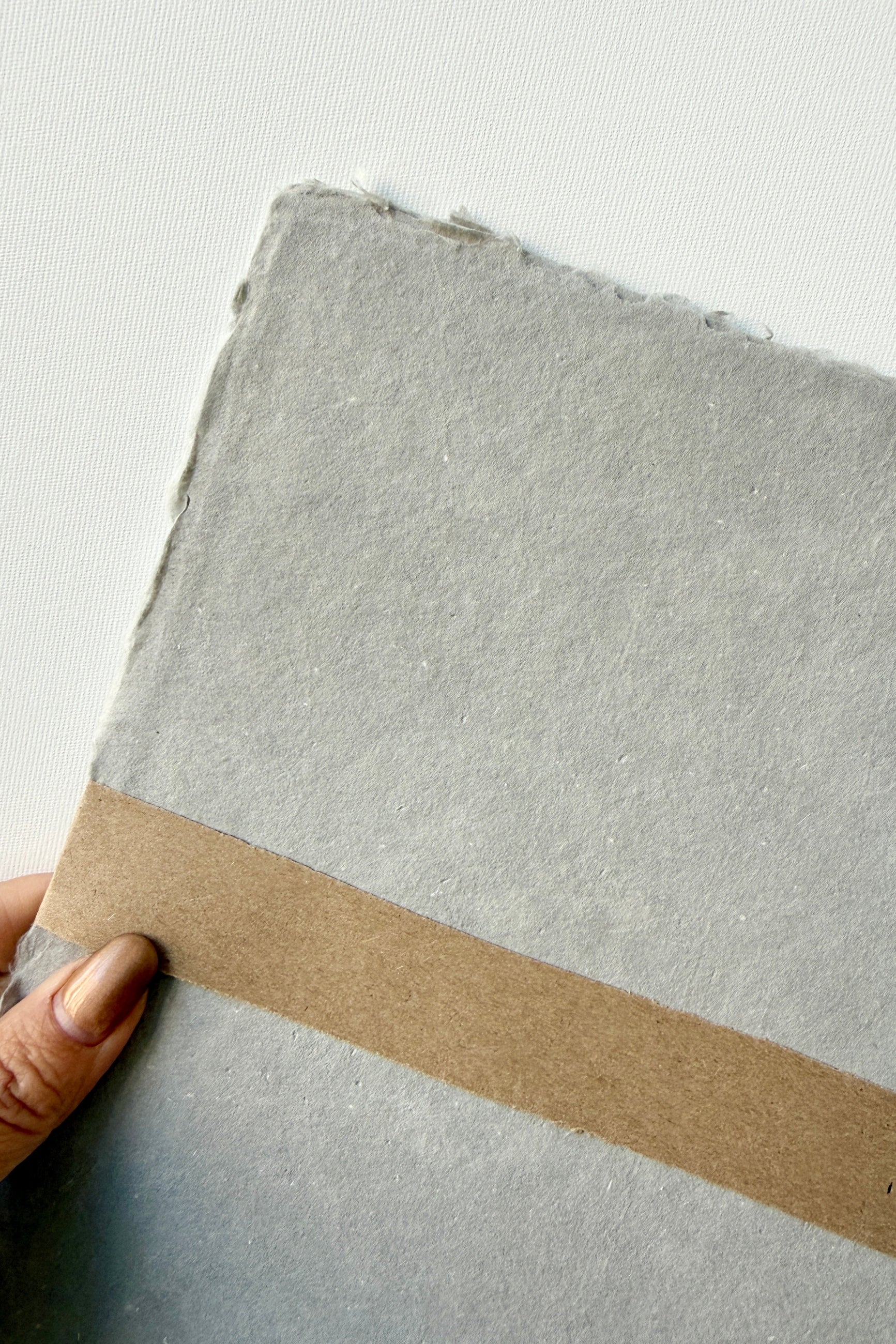 Hand holding a Handmade Paynes Grey Paper Sheet Set in 8x10 by Sustainable Paper & Craft ©Sprout Home