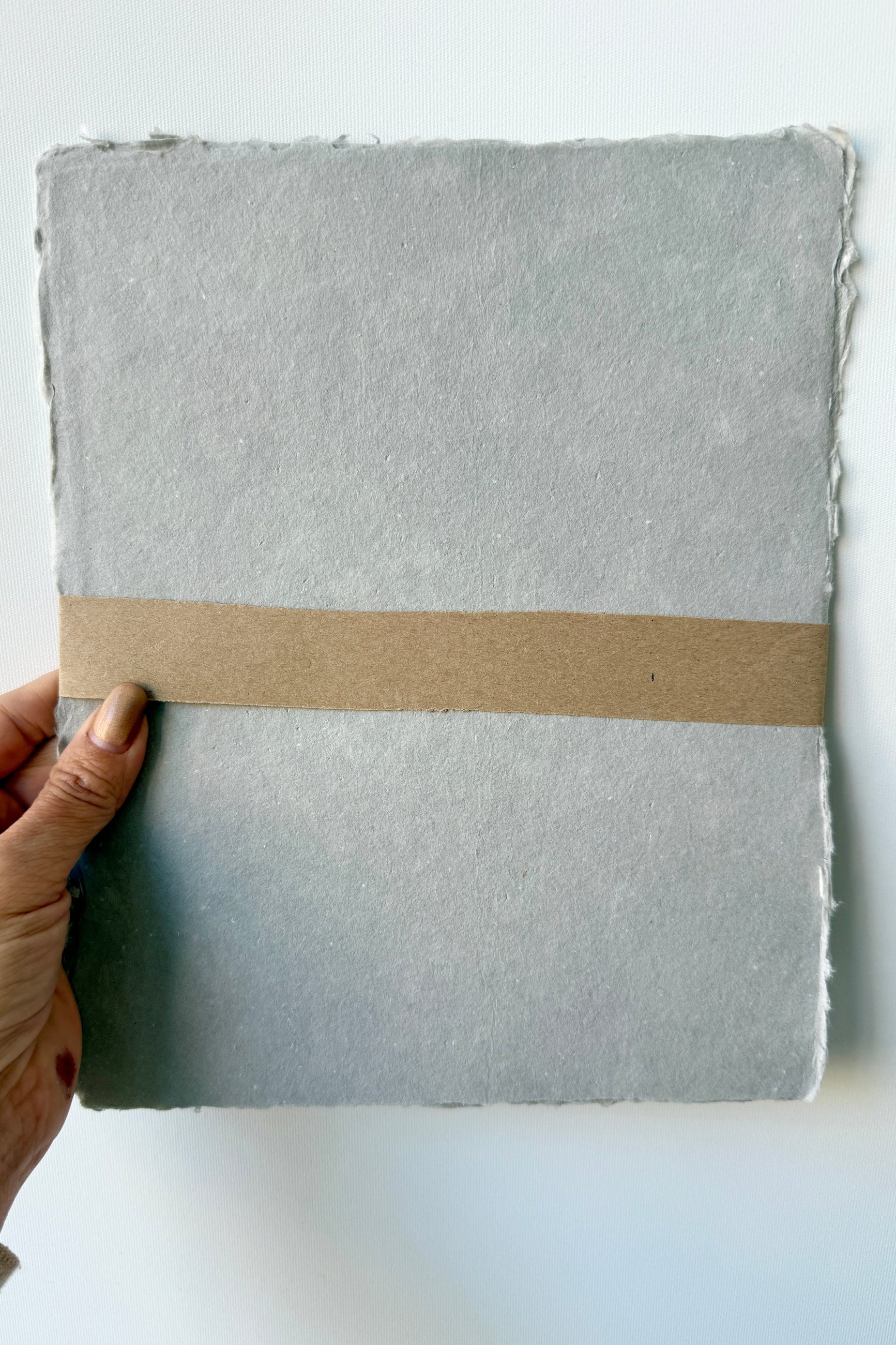 Handmade Paynes Grey Paper Sheet Set in 8x10 by Sustainable Paper + Craft held by a hand on a white background ©Sprout Home