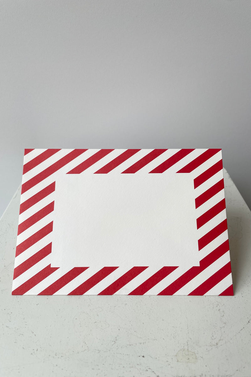 Red and white striped envelope with blank white rectangle on face of envelope. 