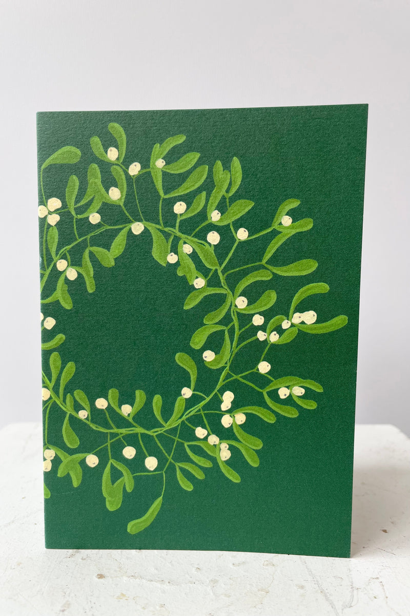 Wreath of white misteltoe berries on green background. Blank inside.